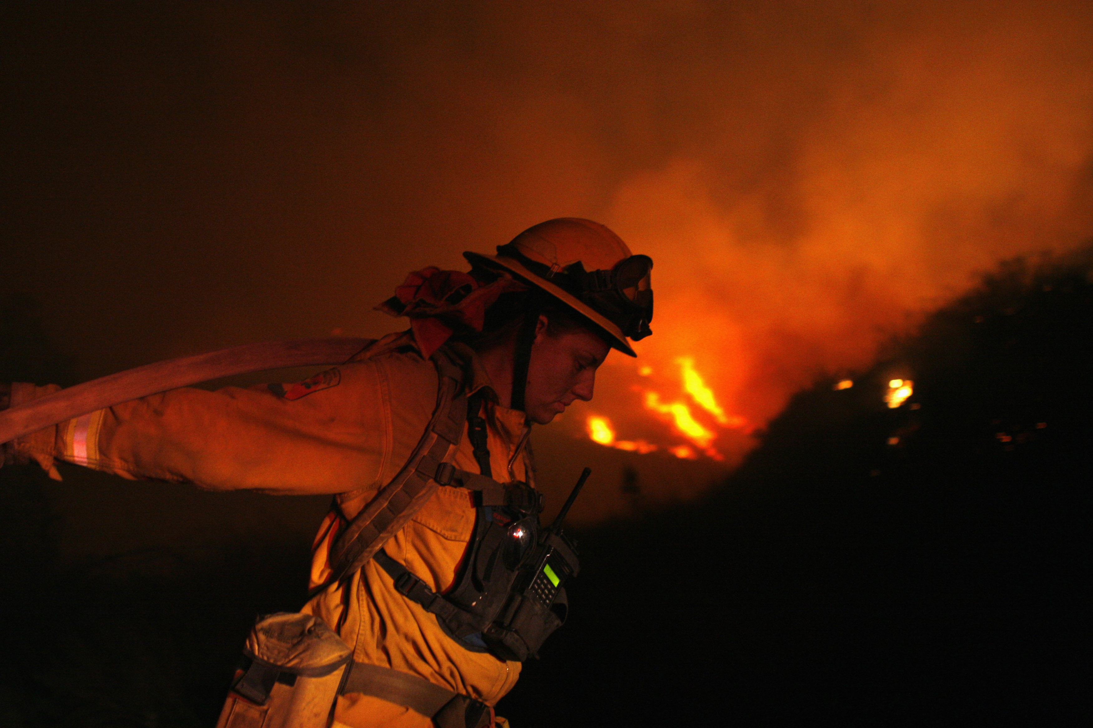 A firefighter pulls a water hose as she battles the Poomacha wildfire on the La Jolla Indian Reservation in Southern California, October 25, 2007. REUTERS/Joshua Lott