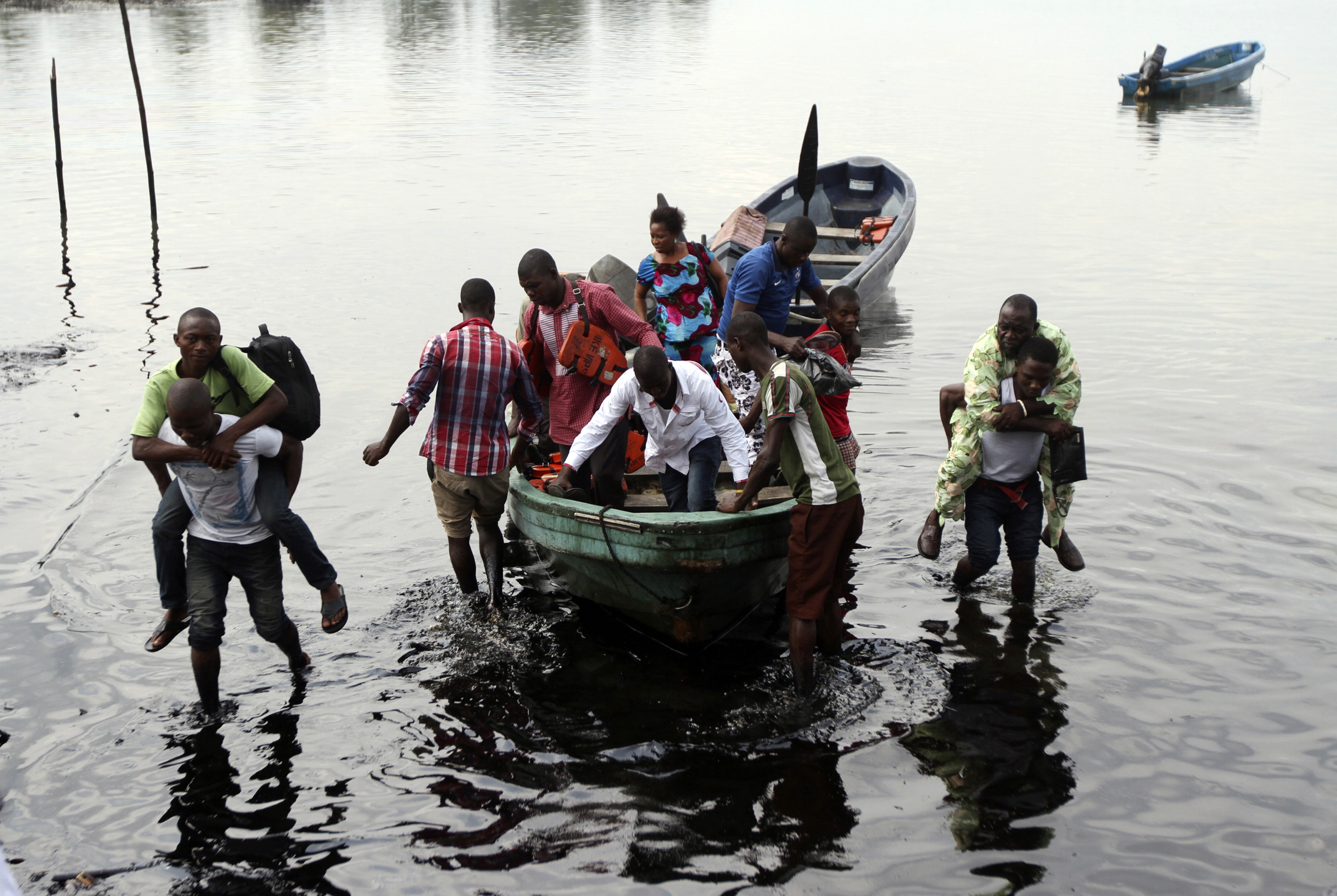 Boat guides carry people through polluted water as passengers disembark at the shore of Bodo creek in Ogoniland. December 4, 2012. REUTERS/Akintunde Akinleye