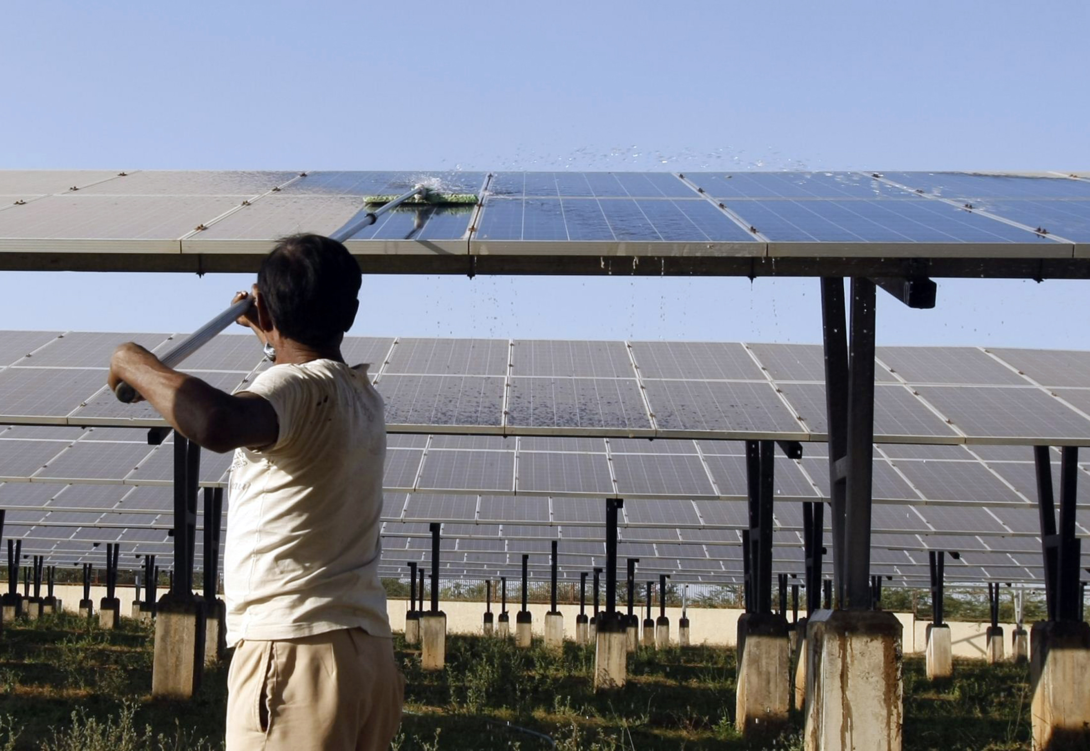 A worker cleans photovoltaic solar panels inside a solar power plant at Raisan village near Gandhinagar, in the western Indian state of Gujarat, February 11, 2014