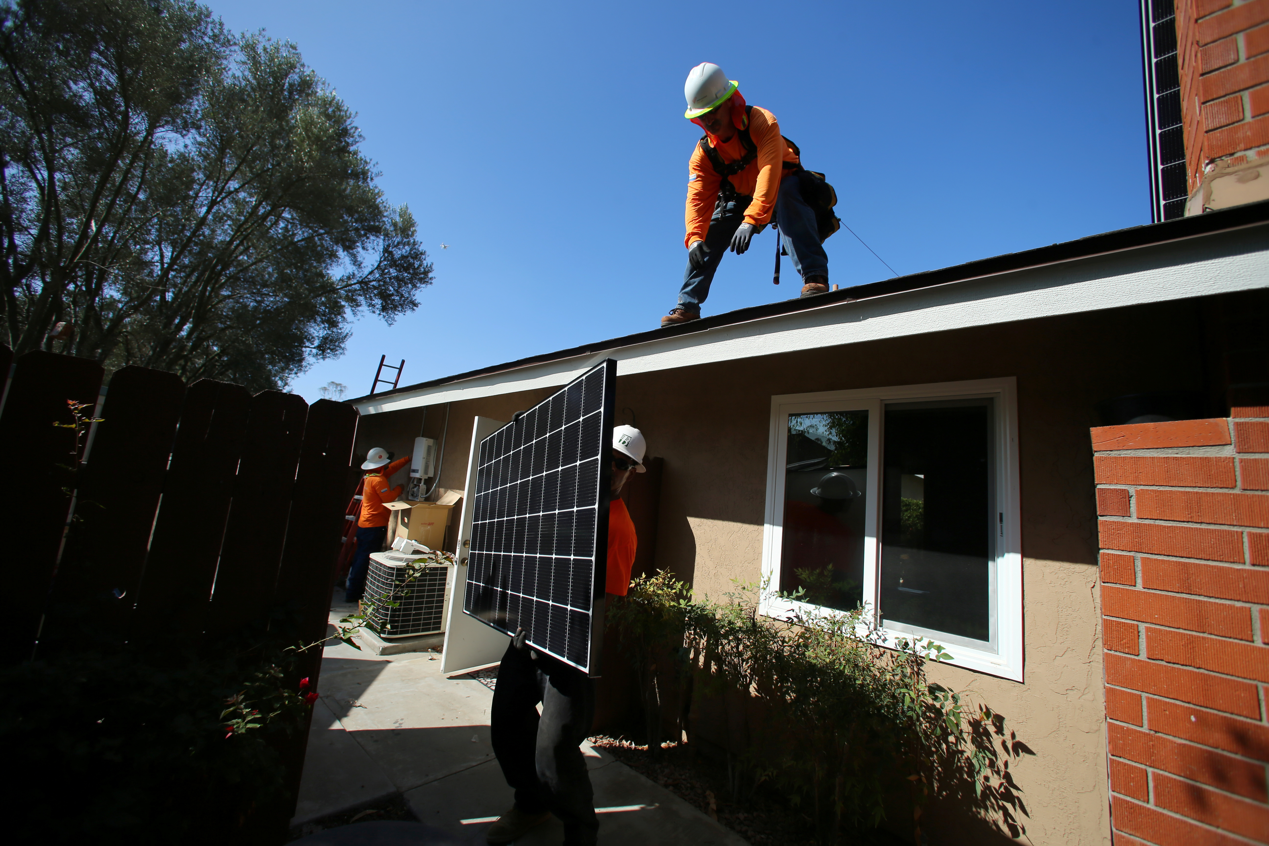 Workers lift a solar panel onto a roof during a residential solar installation in Scripps Ranch, San Diego, California, U.S. October 14, 2016. REUTERS/Mike Blake