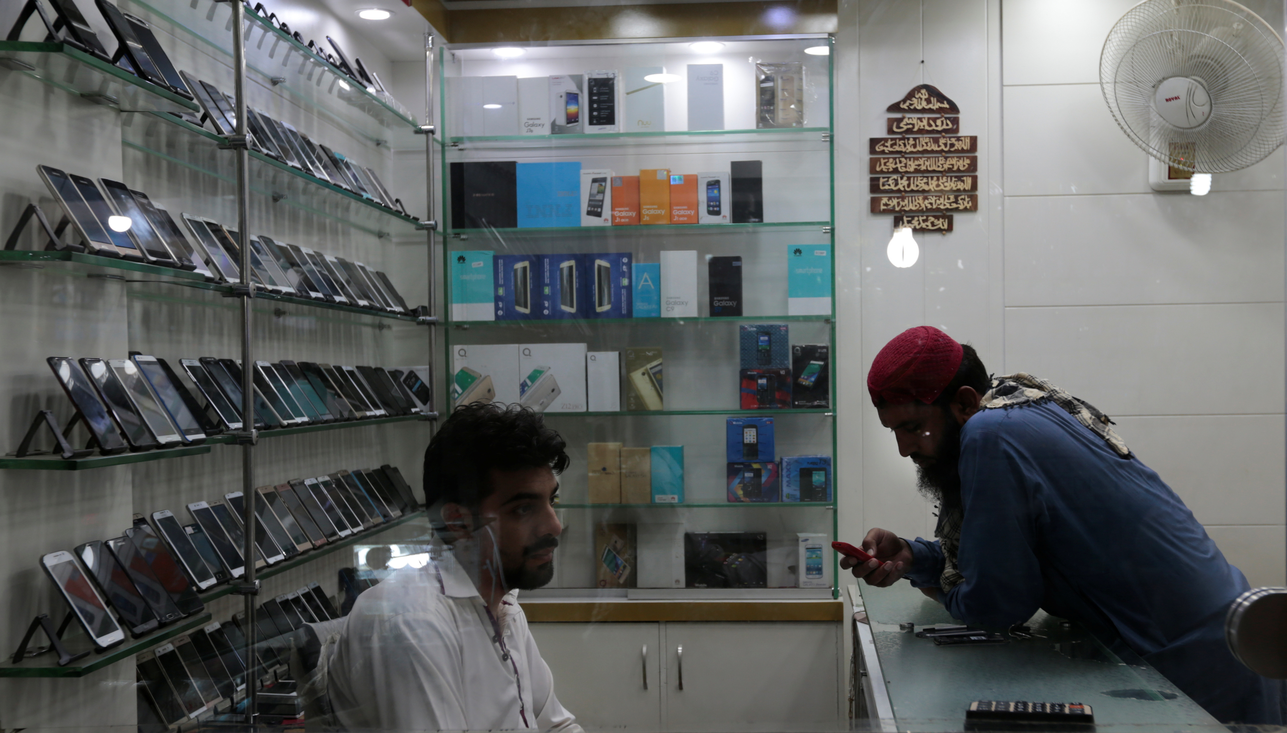 A customer looks at a mobile phone at a shop in Rawalpindi, Pakistan July 4, 2017. REUTERS/Caren Firouz