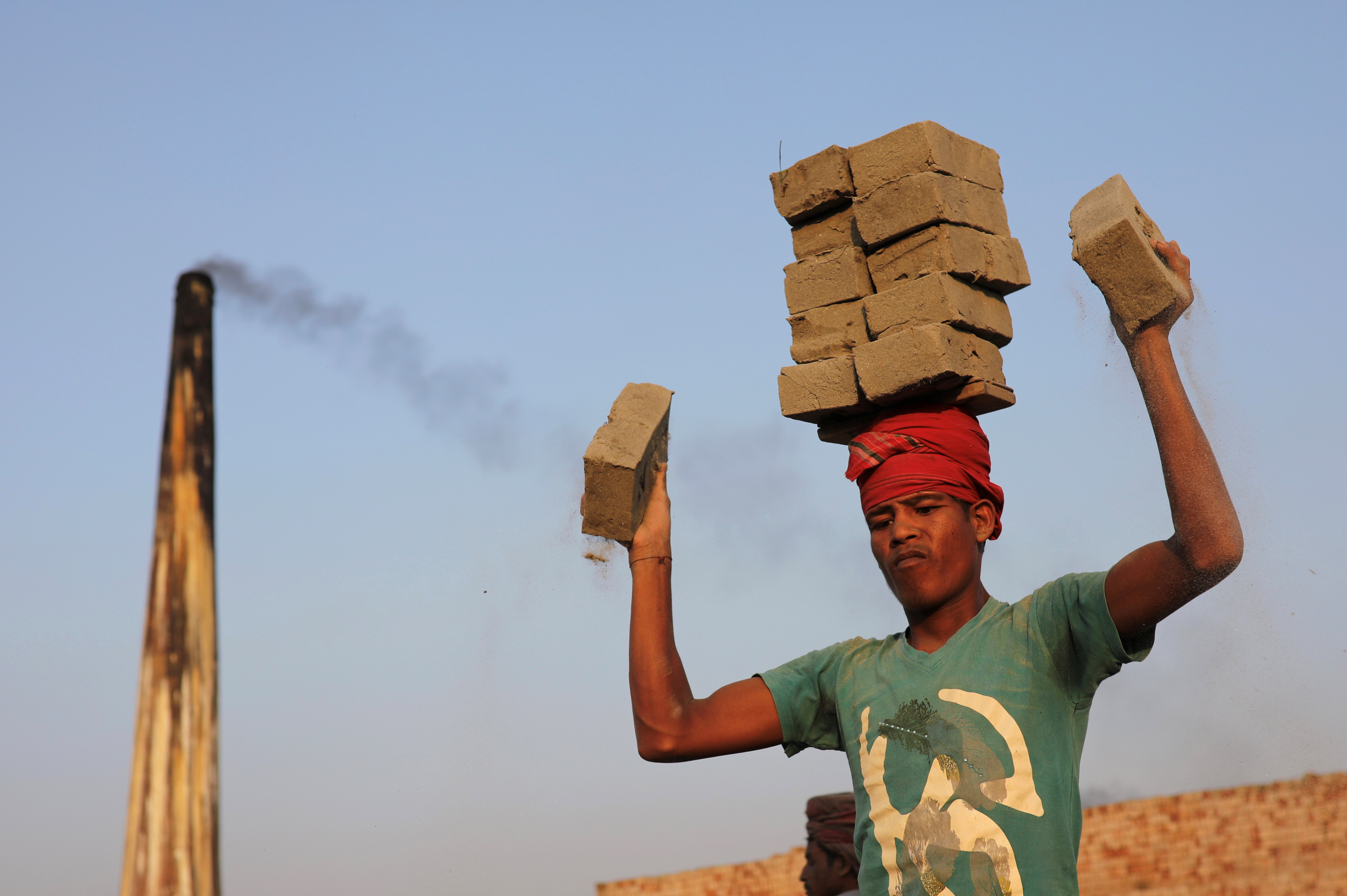 A brick factory worker carries brick on his head in Munshiganj near Dhaka, Bangladesh March 9, 2018. REUTERS/Mohammad Ponir Hossain