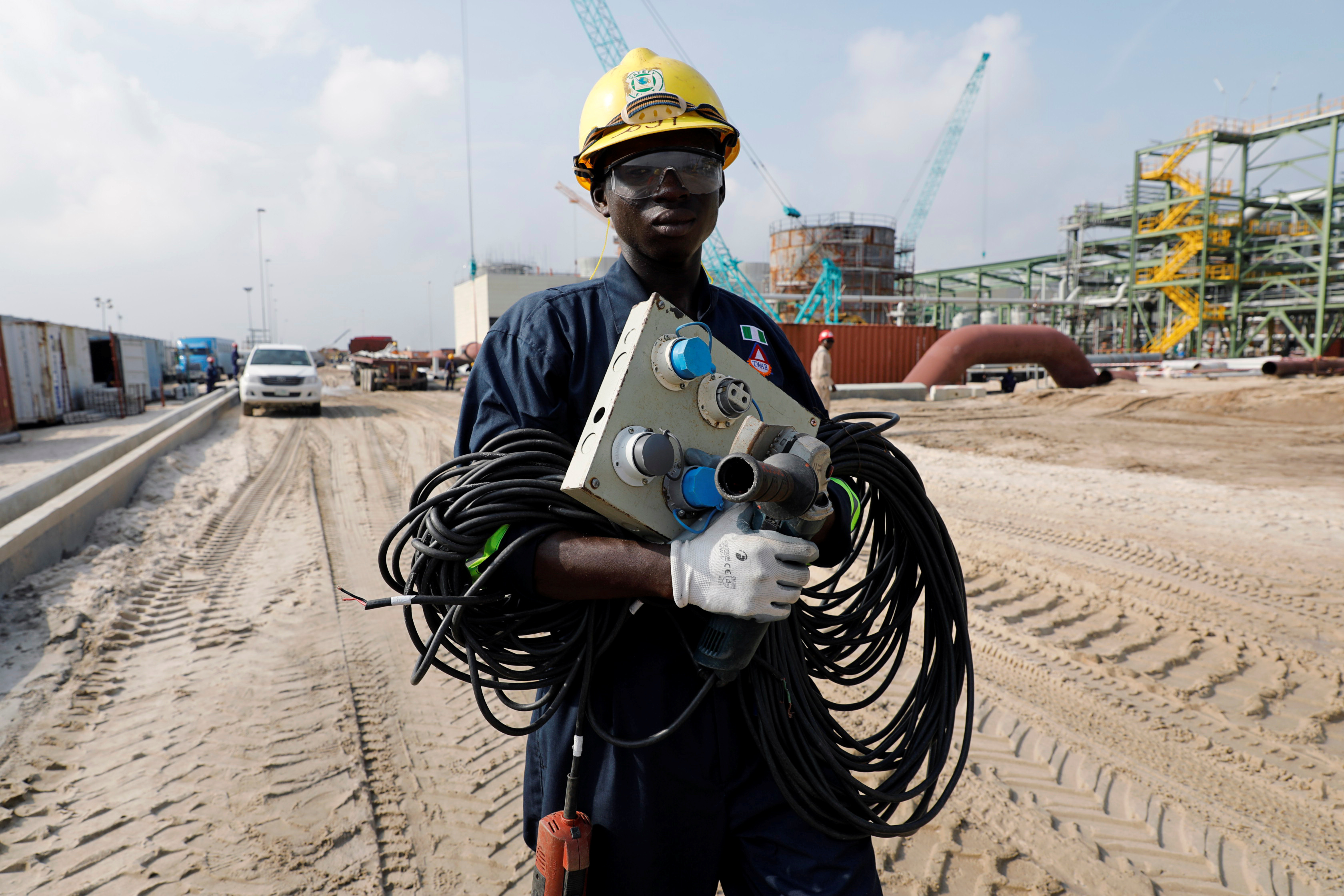A construction worker holds electrical wires as he walks through the Dangote Oil Refinery under construction in Ibeju Lekki district, on the outskirts of Lagos, Nigeria July 5, 2018. Picture taken July 5, 2018. REUTERS/Akintunde Akinleye