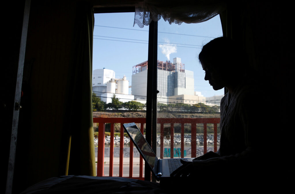 A girl works on her laptop inside of her house in front of the refinery of Puerto Ventanas in Ventanas, Chile September 1, 2018. REUTERS/Rodrigo Garrido