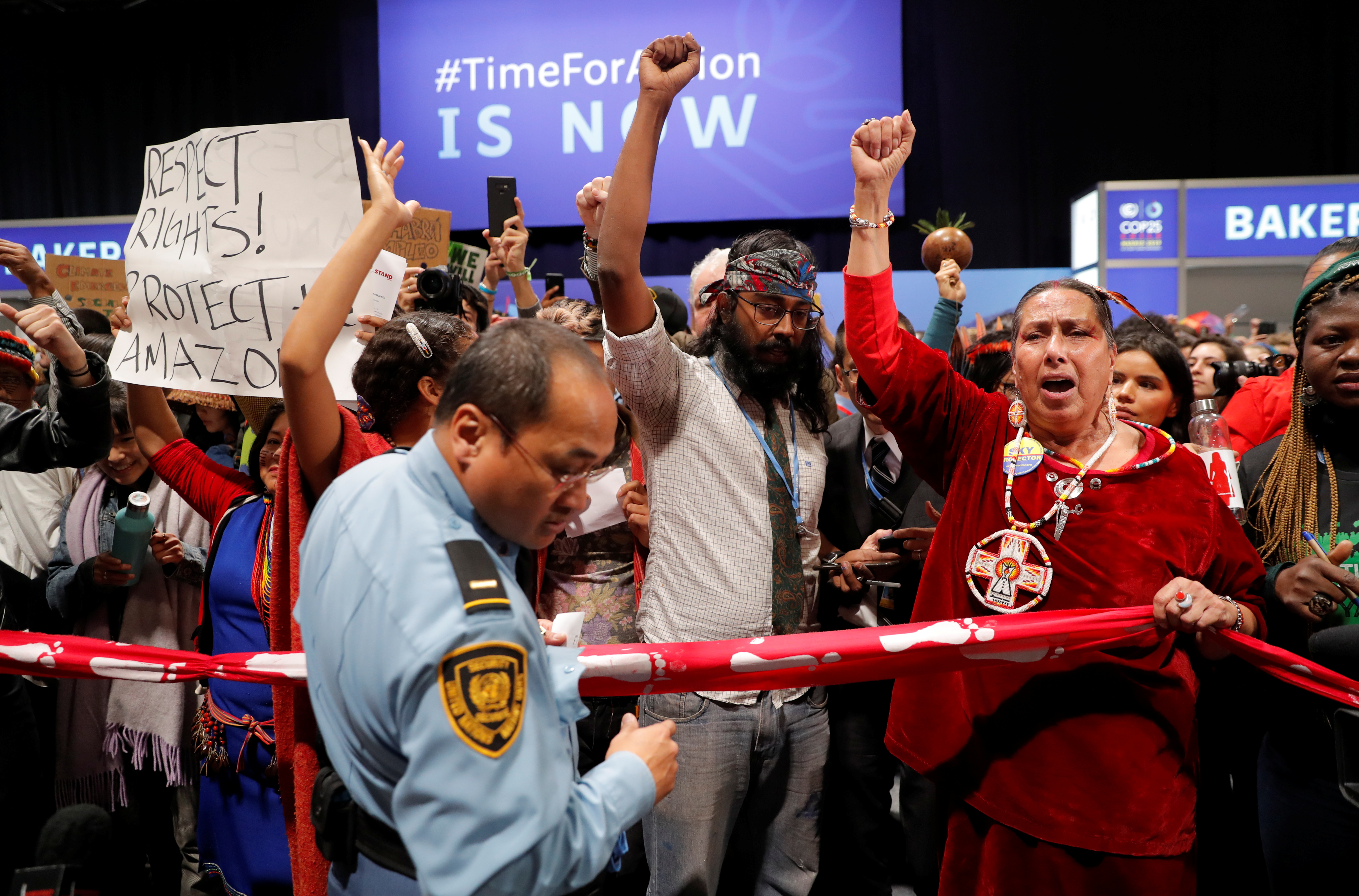 A security officer stands in front of climate activists gesturing outside the plenary room baker during the U.N. Climate Change Conference (COP25) in Madrid, Spain December 11, 2019. REUTERS/Susana Vera