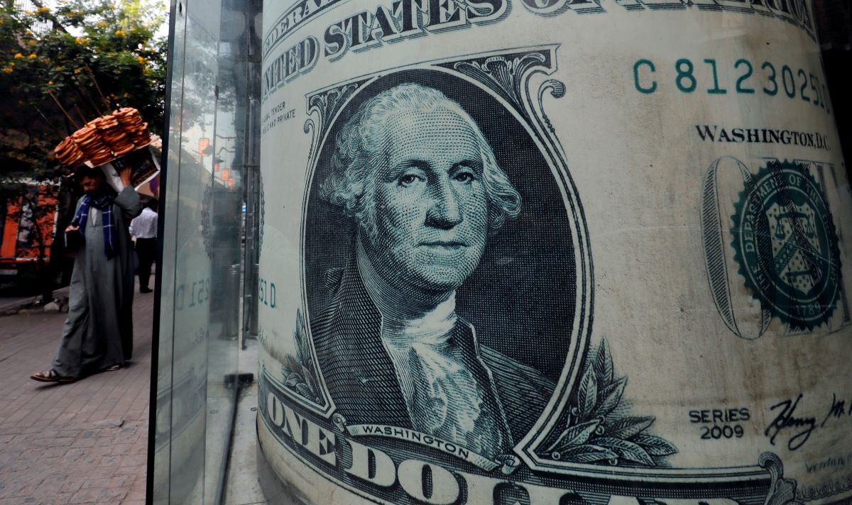 A street vendor, selling bread, walks in front of a currency exchange bureau advertisement showing an image of the U.S. dollar in Cairo, Egypt, December 17, 2019