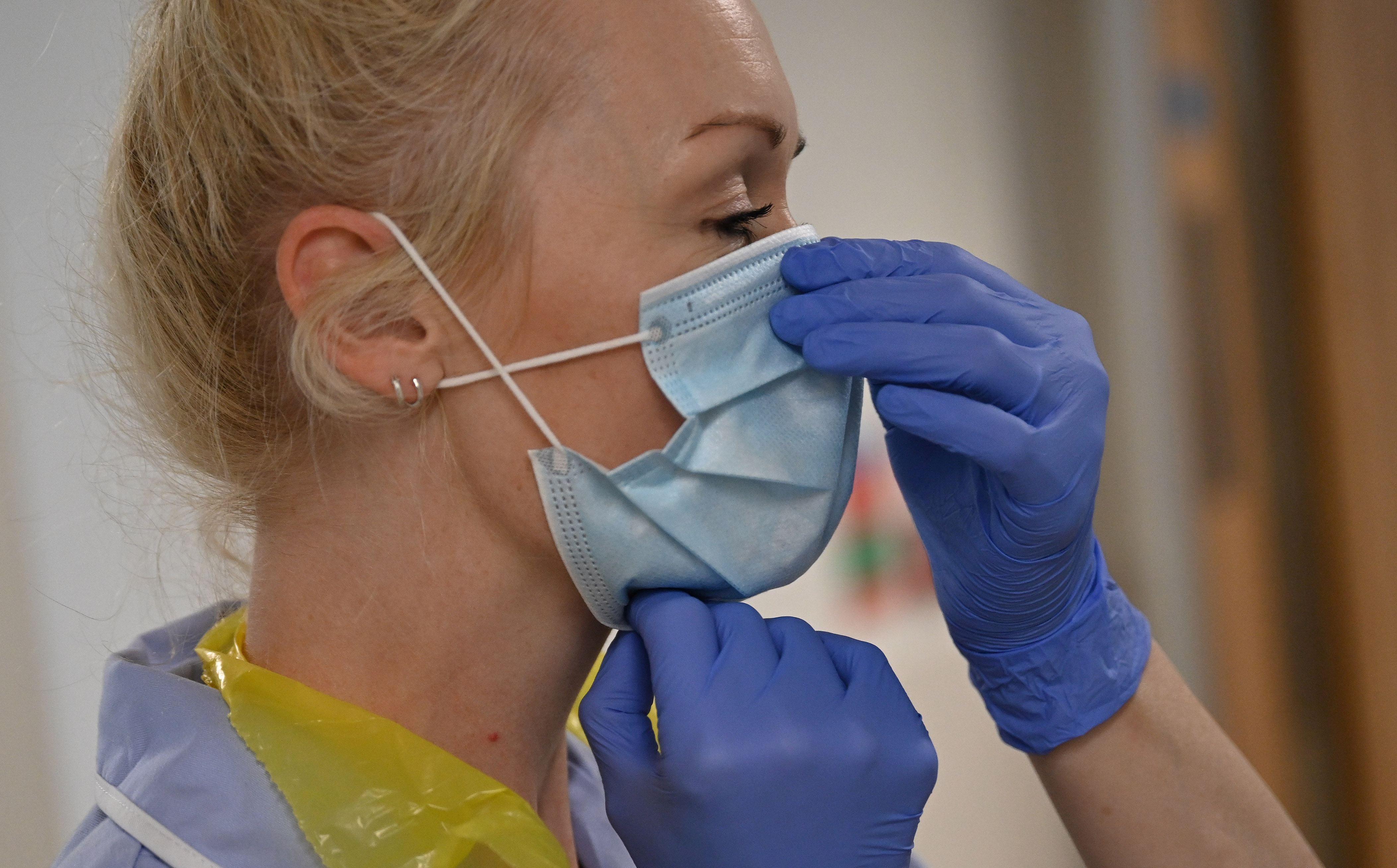 A health worker adjusts her mask as she cares for patients during the COVID pandemic in Cambridge, Britain May 5, 2020. Neil Hall/Pool via REUTERS