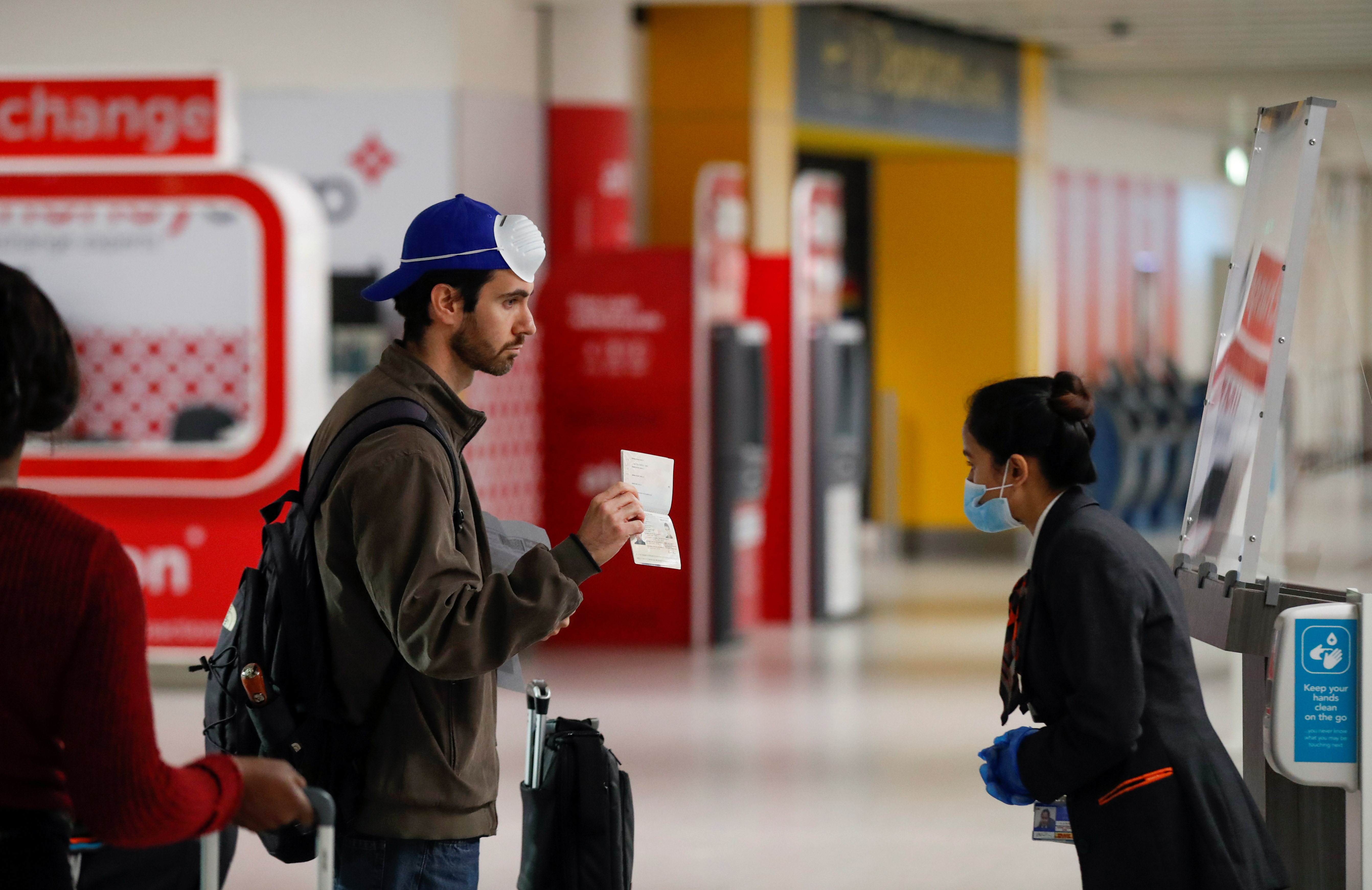 A passenger shows his passport to a staff member at Gatwick Airport, Britain June 15, 2020. REUTERS/Peter Cziborra