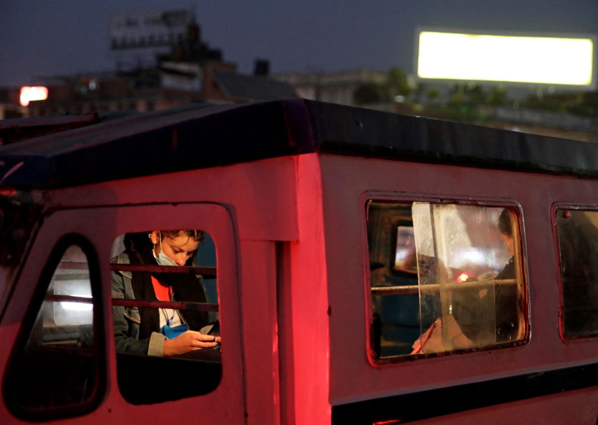 A woman wearing a protective face mask uses her mobile phone inside a public transport vehicle, amidst the outbreak of the coronavirus disease (COVID-19), in Lalitpur, Nepal December 27, 2020. REUTERS/Navesh Chitrakar