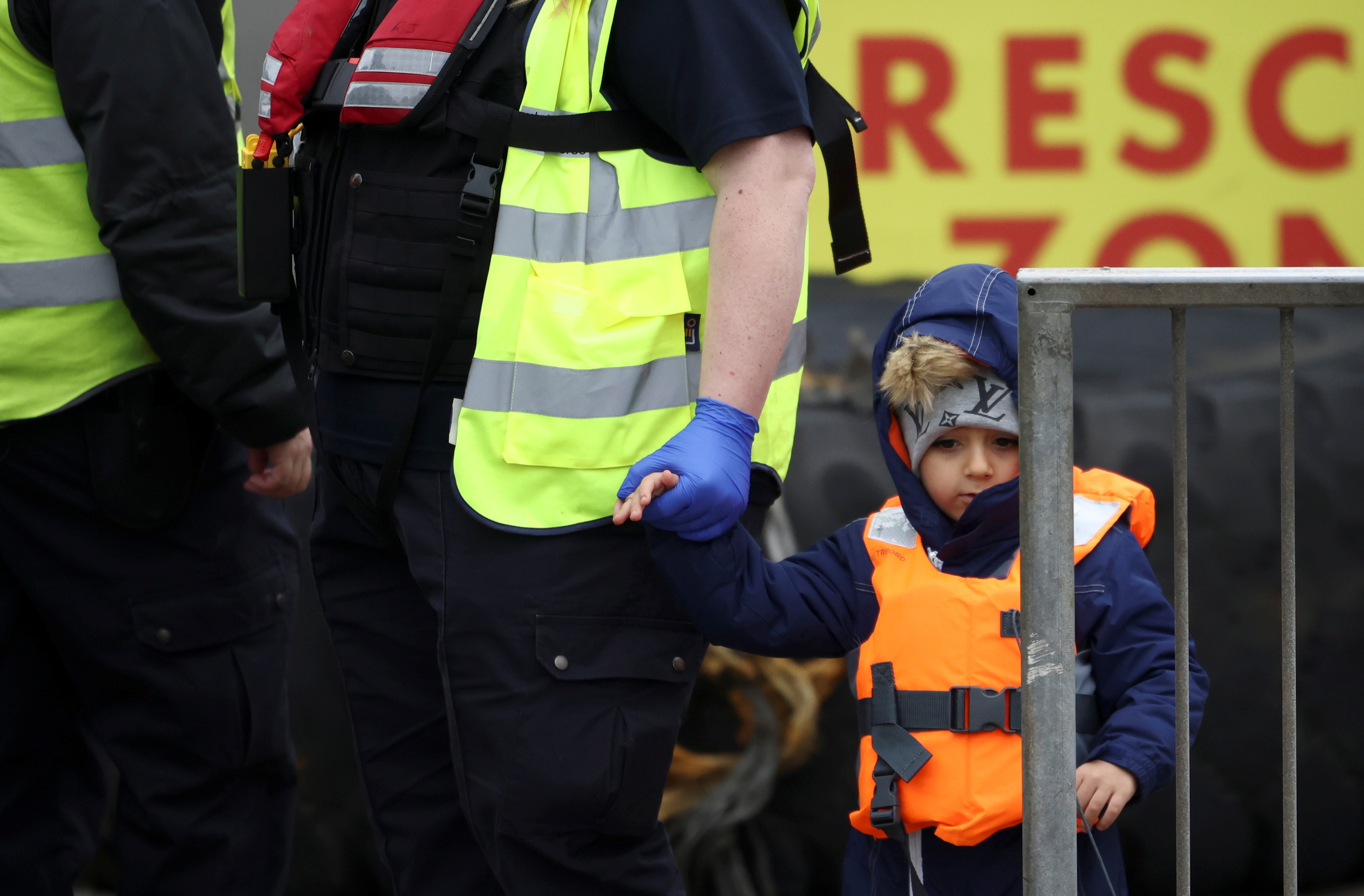A child is escorted, after being brought ashore by a Border Force vessel, in the port of Dover, Britain December 16, 2021. REUTERS/Henry Nicholls.