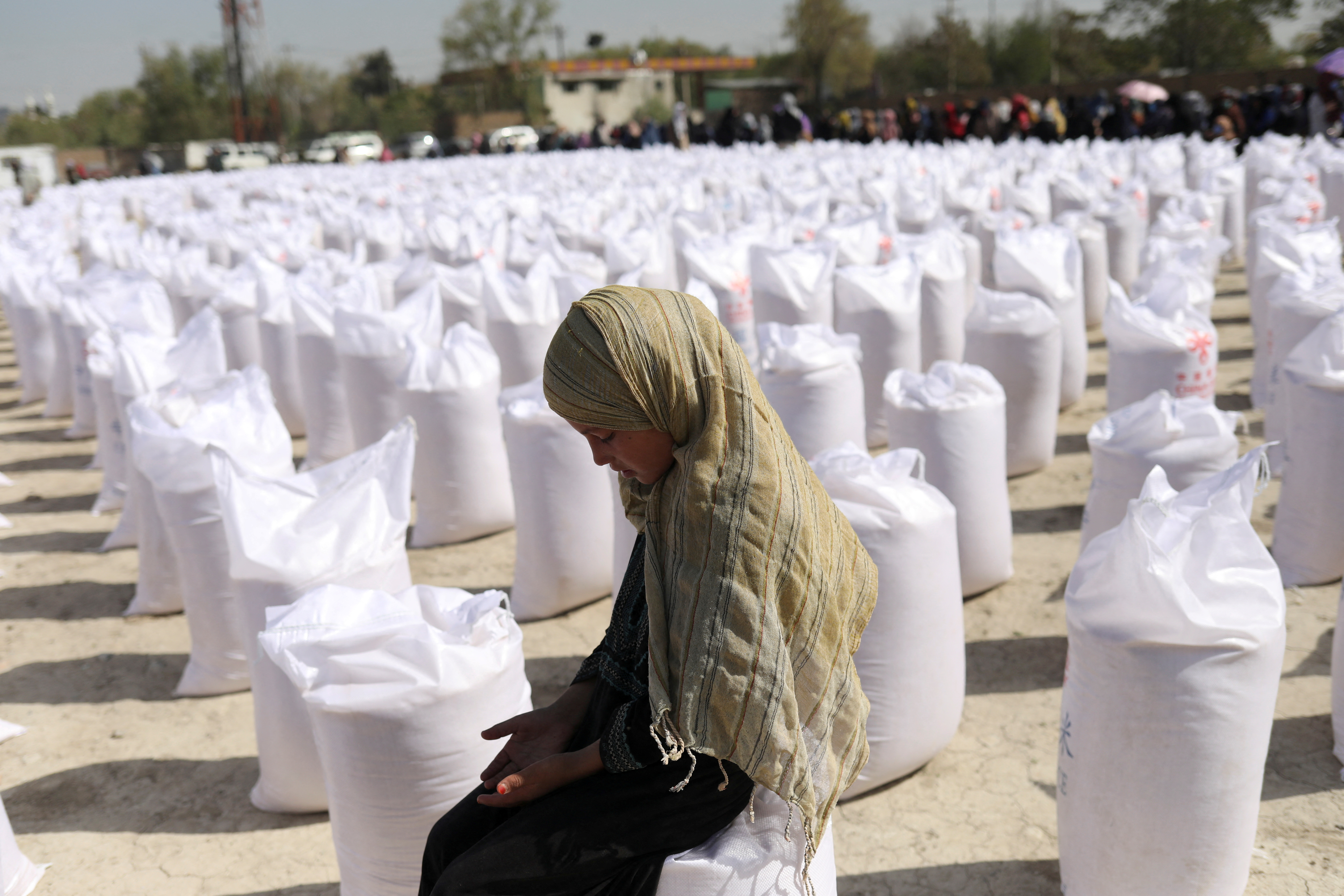 An Afghan girl waits to receive a rice sack, as part of humanitarian aid sent by China to Afghanistan, at a distribution centre in Kabul, Afghanistan, April 7, 2022. REUTERS/Ali Khara