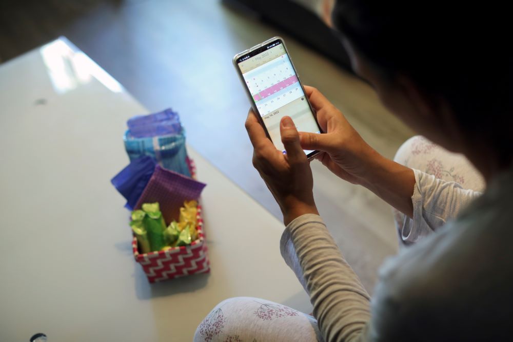 A woman poses as she observes a period calendar tracker app on her mobile phone at her home May 16, 2022. REUTERS/Isabel Infantes