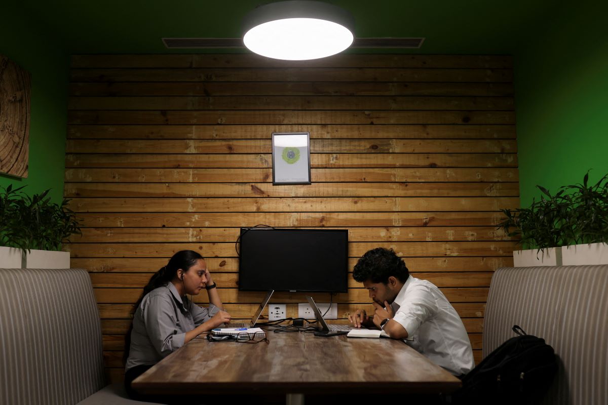 People sit and work on their laptops at an office in Gurugram, India, June 13, 2023