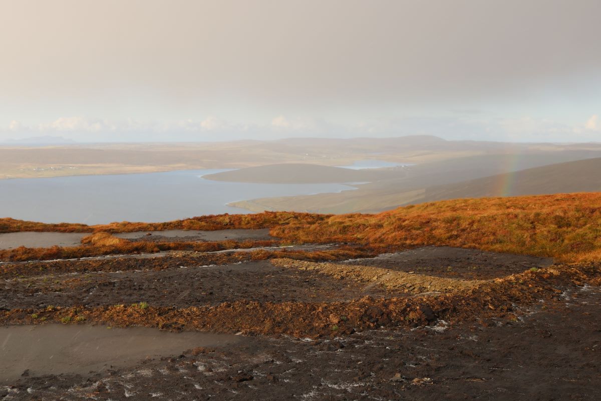 A rainbow shines over bare peat at a Peatland ACTION restoration site, which has been dammed to hold water on the hill, near Tresta hamlet, Shetland, Scotland, November 1, 2023. Thomson Reuters Foundation/Jack Graham