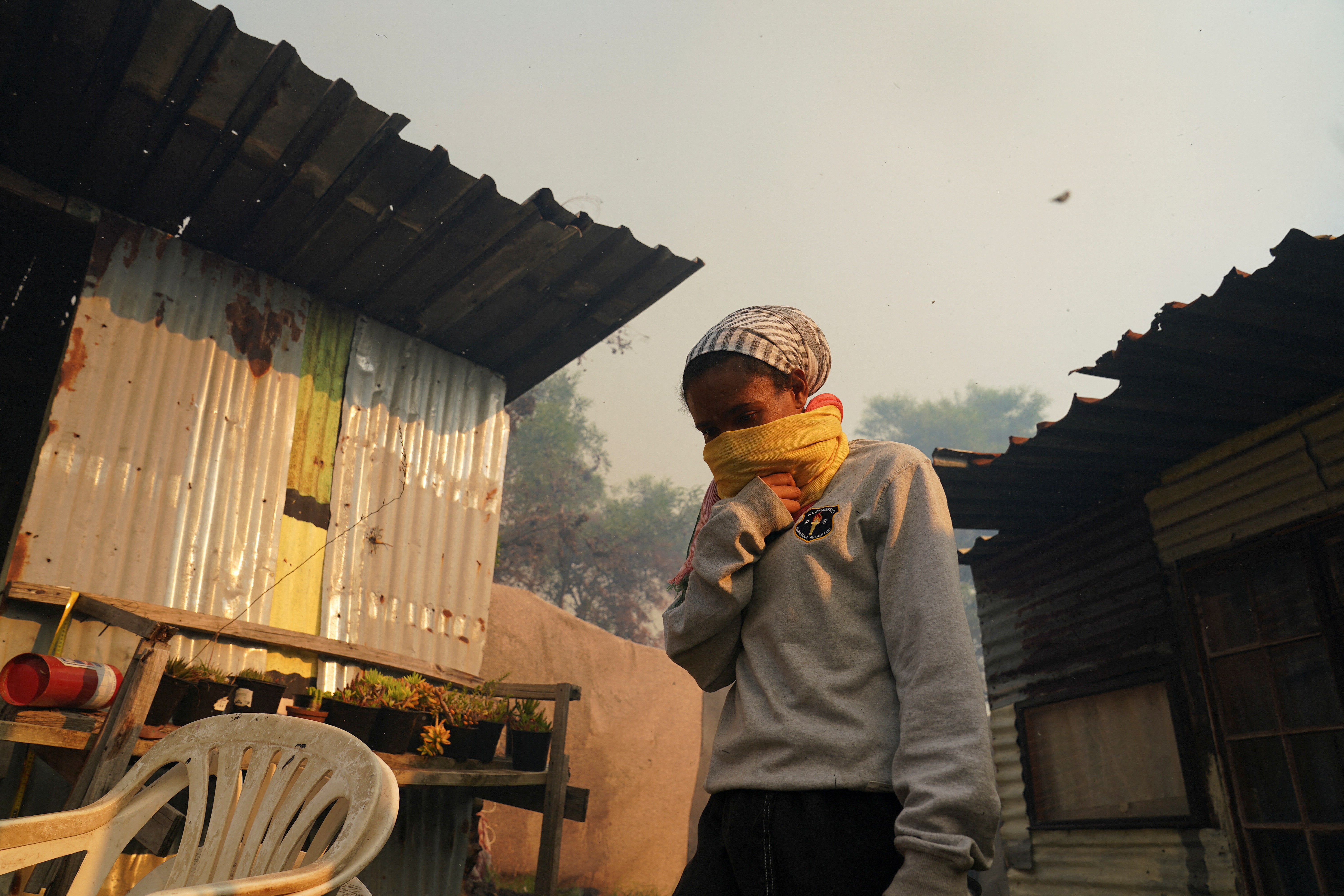 A resident covers her mouth and nose amid thick smoke from a mountain fire in Ocean View, Cape Town, South Africa January 22, 2024. REUTERS/Nic Bothma