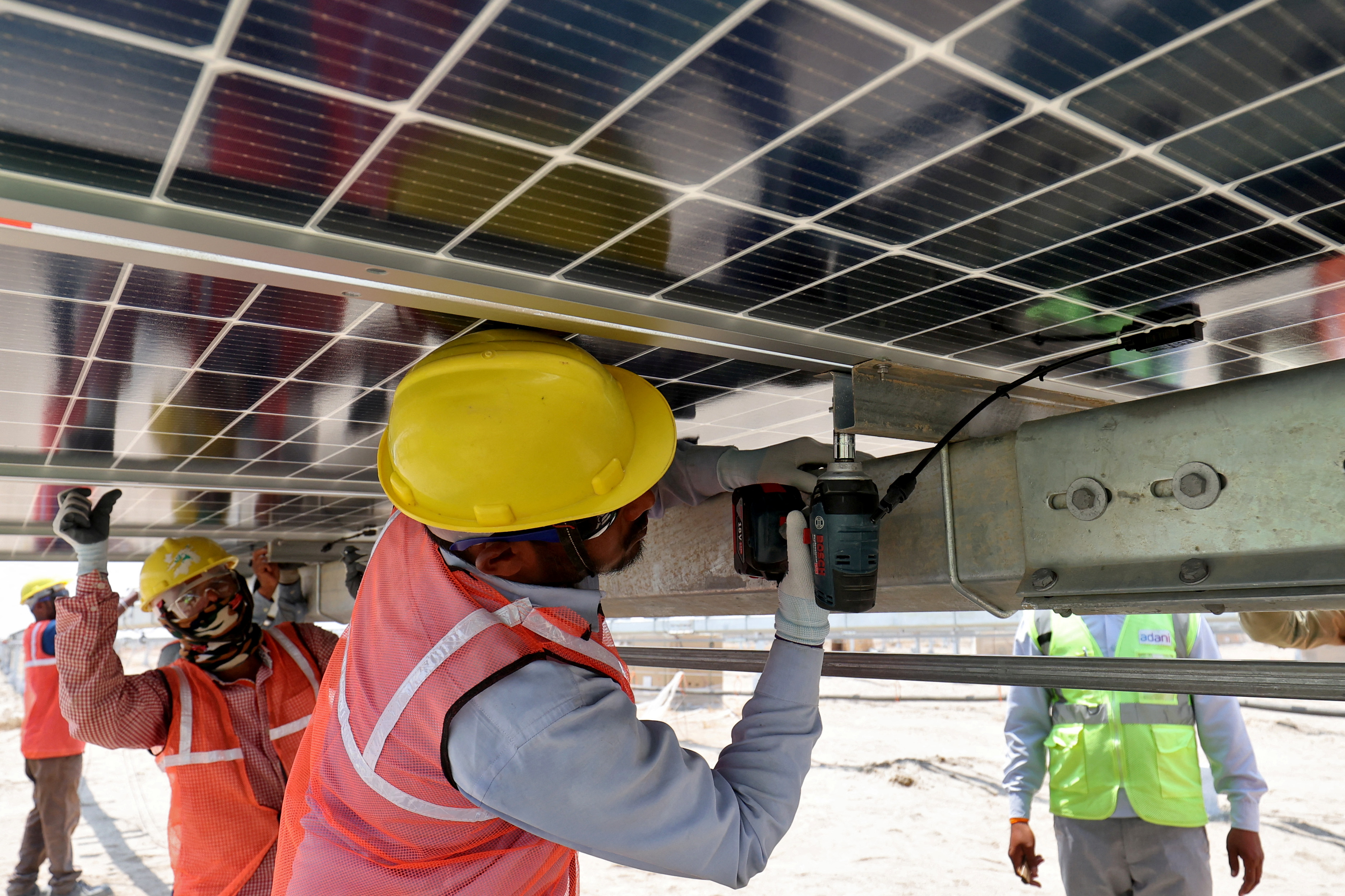 Workers install solar panels at the Khavda Renewable Energy Park of Adani Green Energy Ltd (AGEL), in Khavda, India, April 12, 2024.REUTERS/Amit Dave