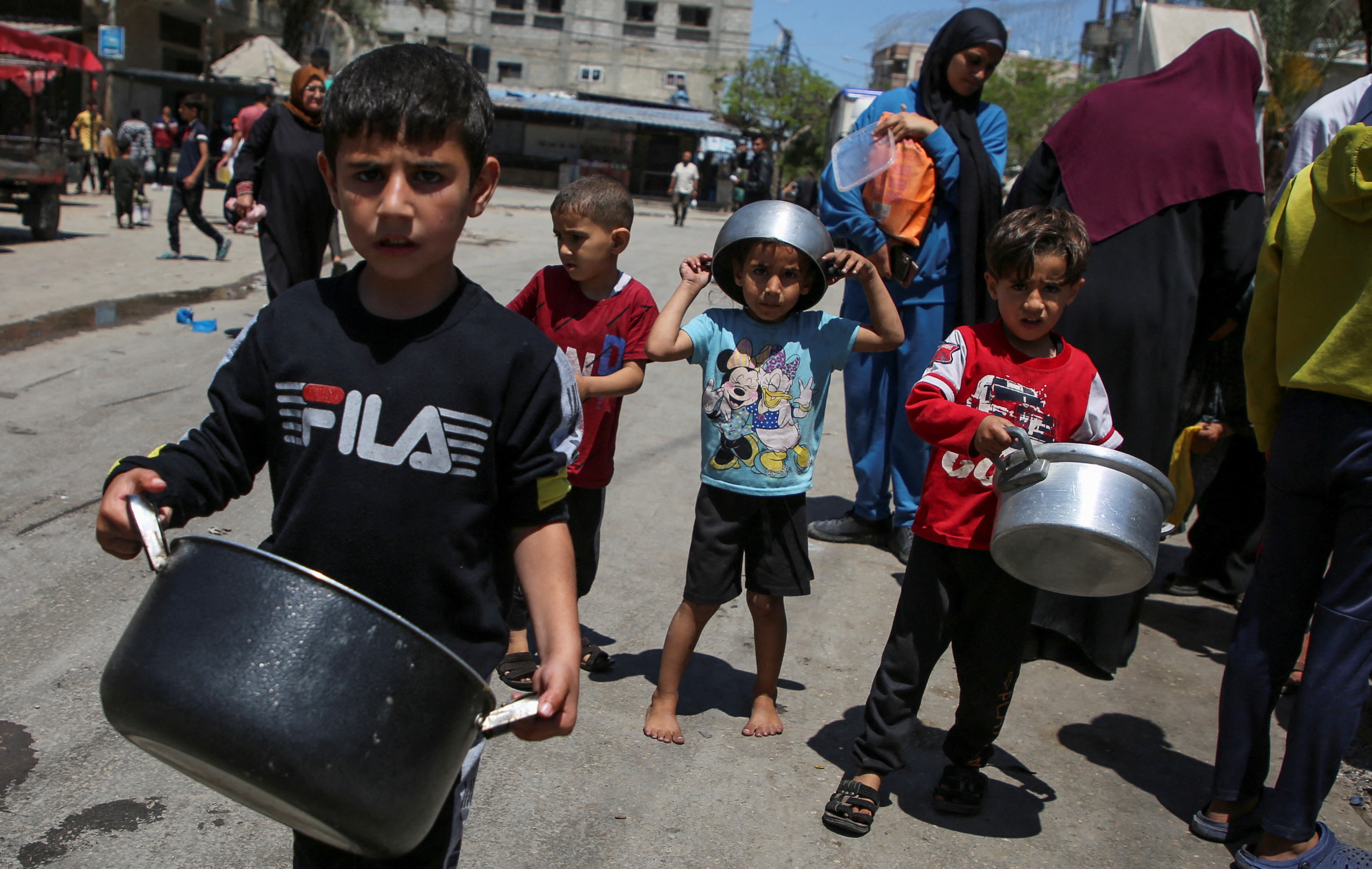 Palestinian children carrying pots wait to receive food cooked by a charity kitchen, amid shortages of aid supplies, as the ongoing conflict between Israel and Hamas continues, in Rafah, in the southern Gaza Strip May 8, 2024. REUTERS/Hatem Khaled