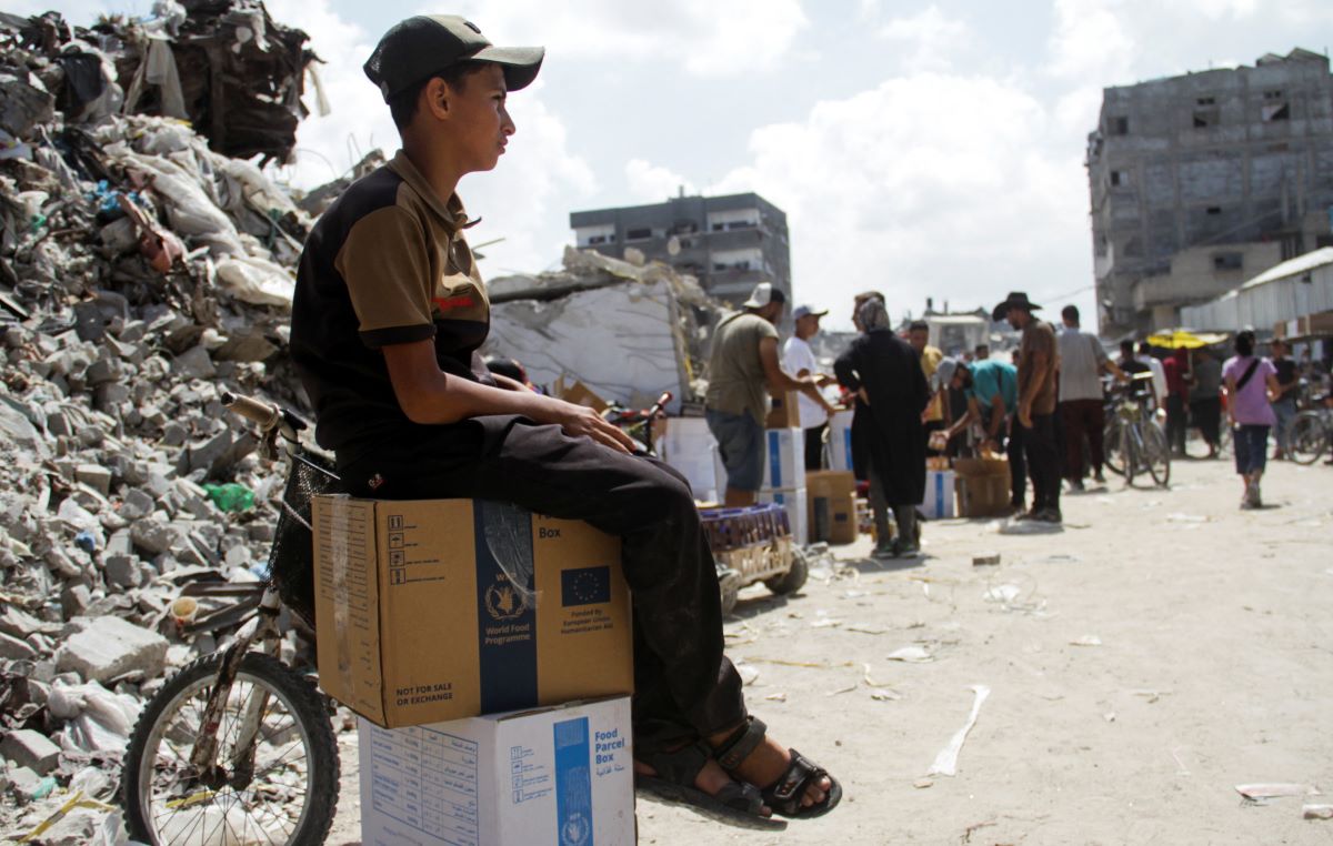 A boy sits on boxes as Palestinians gather to receive aid, including food supplies provided by World Food Program (WFP), outside a United Nations distribution center, amid the Israel-Hamas conflict, in Jabalia in the northern Gaza Strip, August 24, 2024. REUTERS/Mahmoud Issa