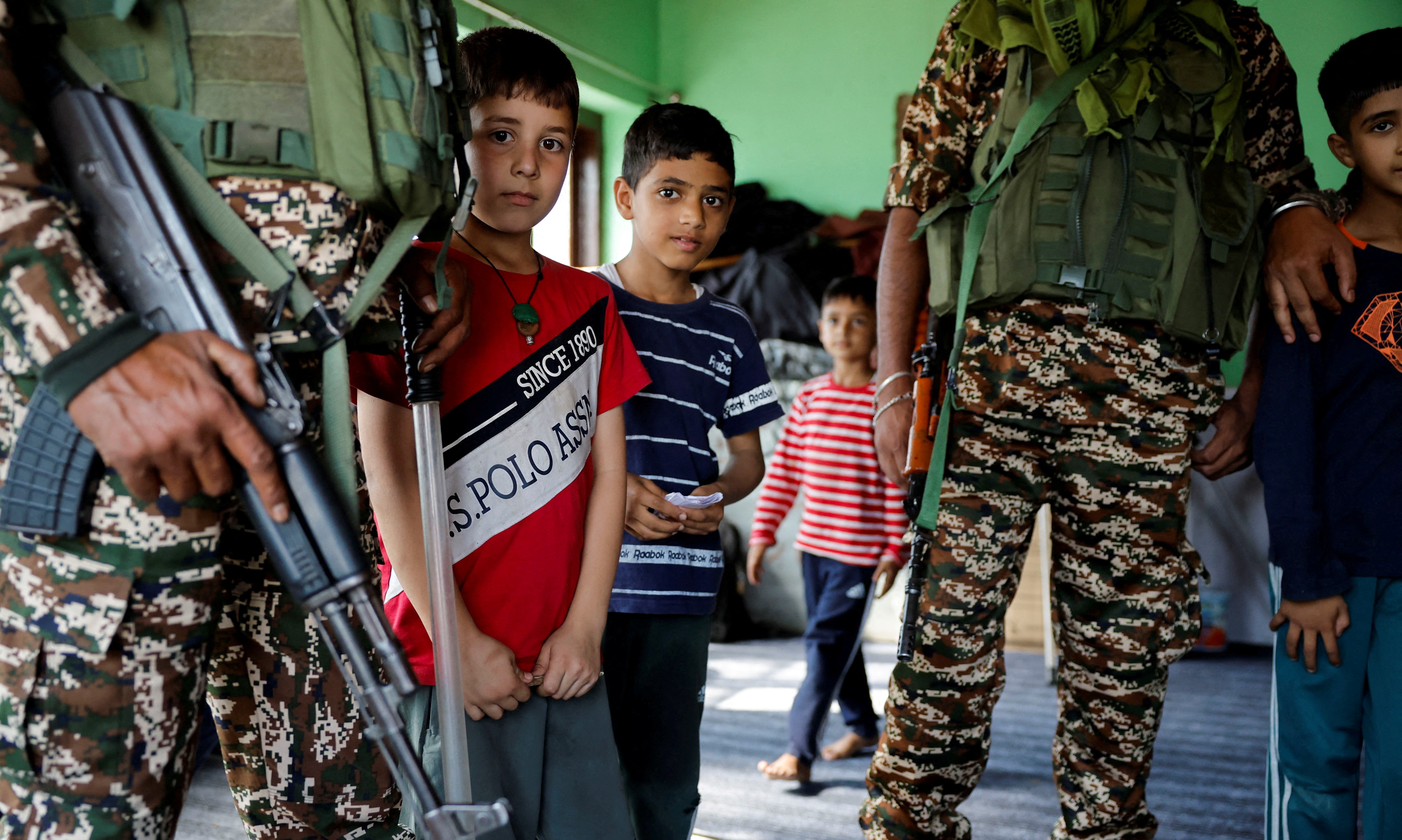 Kashmiri children stand with Indian security personnel in Srinagar September 24, 2024. REUTERS/Sharafat Ali