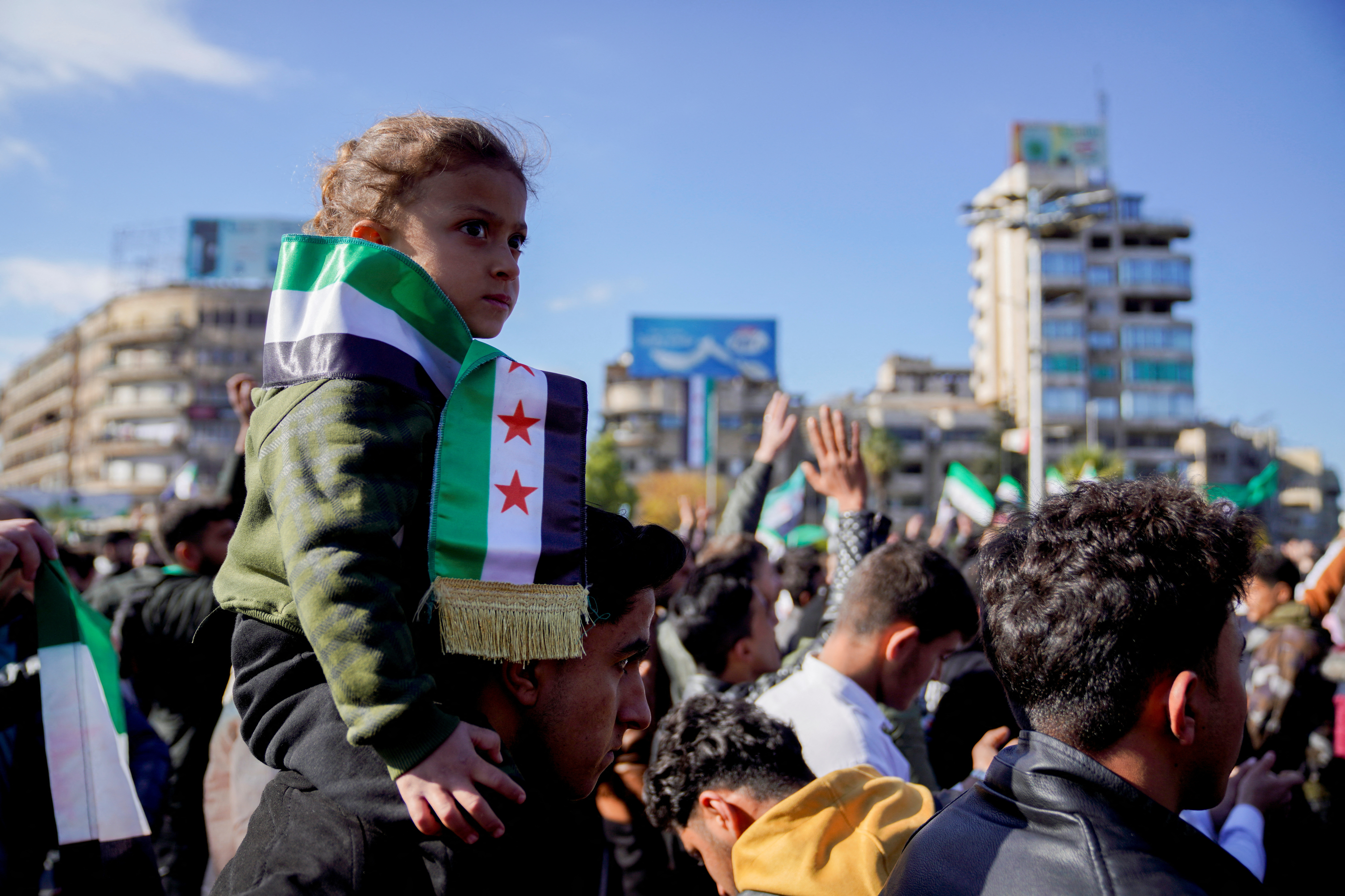 A man carries a child as people gather to celebrate, after fighters of the ruling Syrian body ousted Syria's Bashar al-Assad, in Aleppo, Syria, December 13, 2024. REUTERS/Karam al-Masri