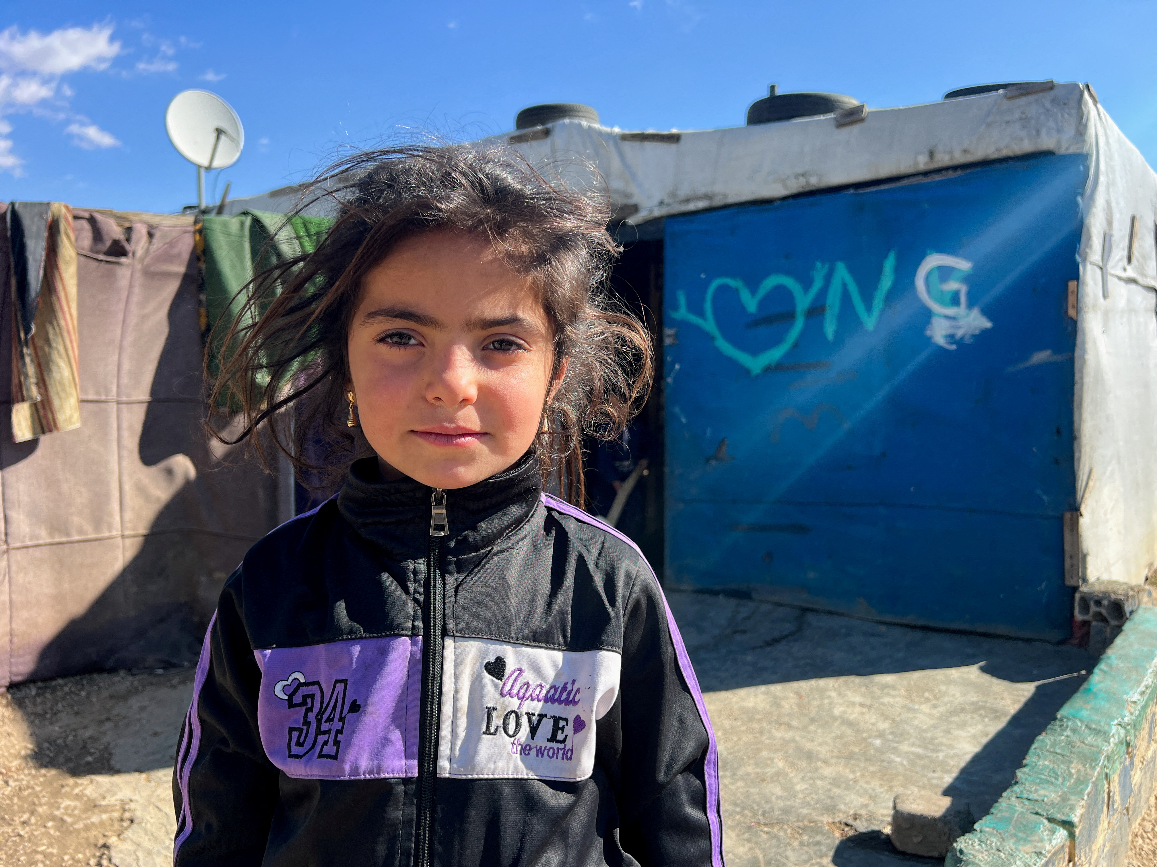 A Syrian refugee girl stands near tents at an informal settlement in Bar Elias, Bekaa Valley, Lebanon, December 13, 2024. REUTERS/Abdelaziz Boumzar