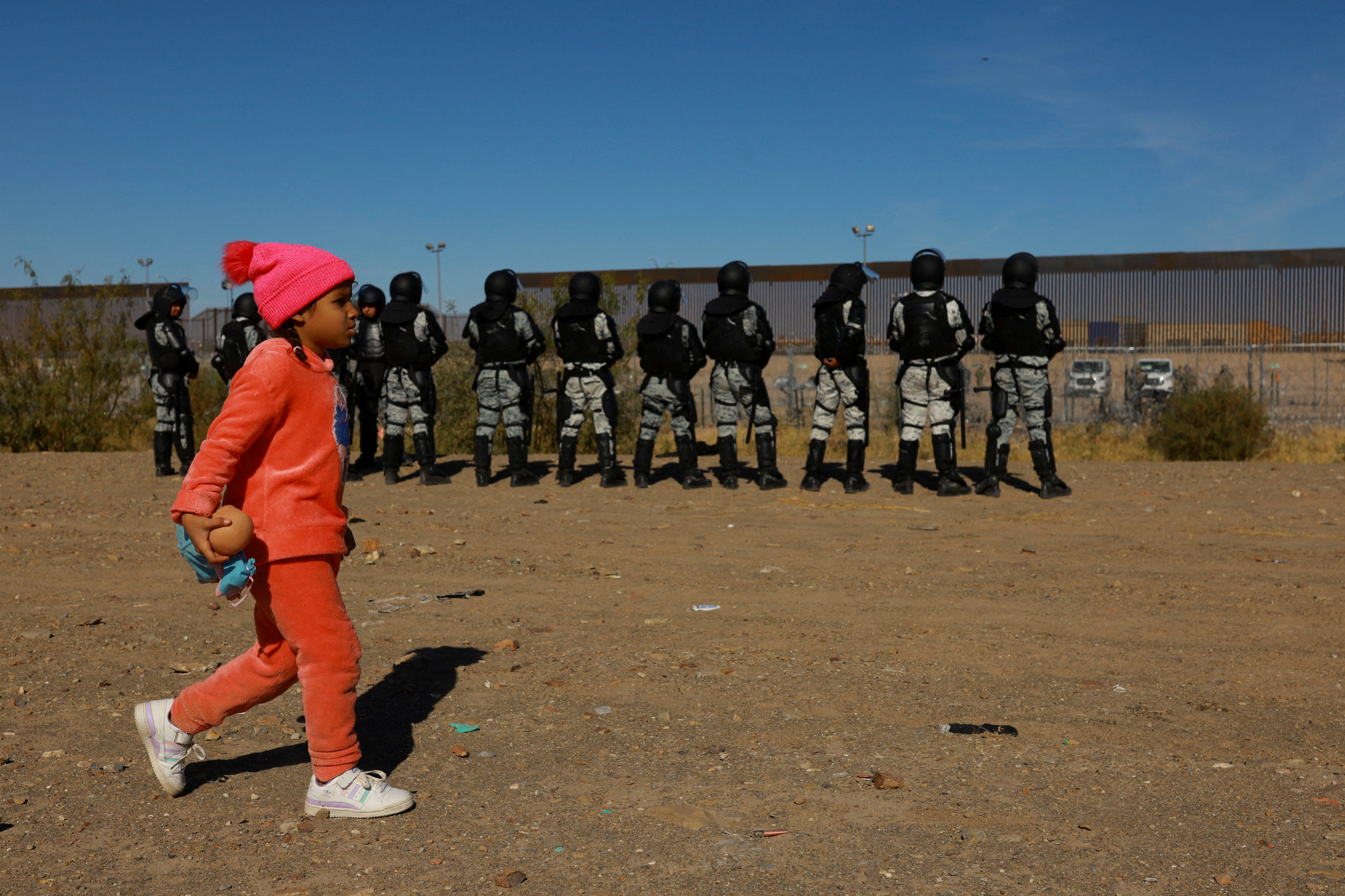 A migrant girl seeking asylum in the United States walks in front of members of the Mexican National Guard in Ciudad Juarez, Mexico December 18, 2024. REUTERS/Jose Luis Gonzalez
