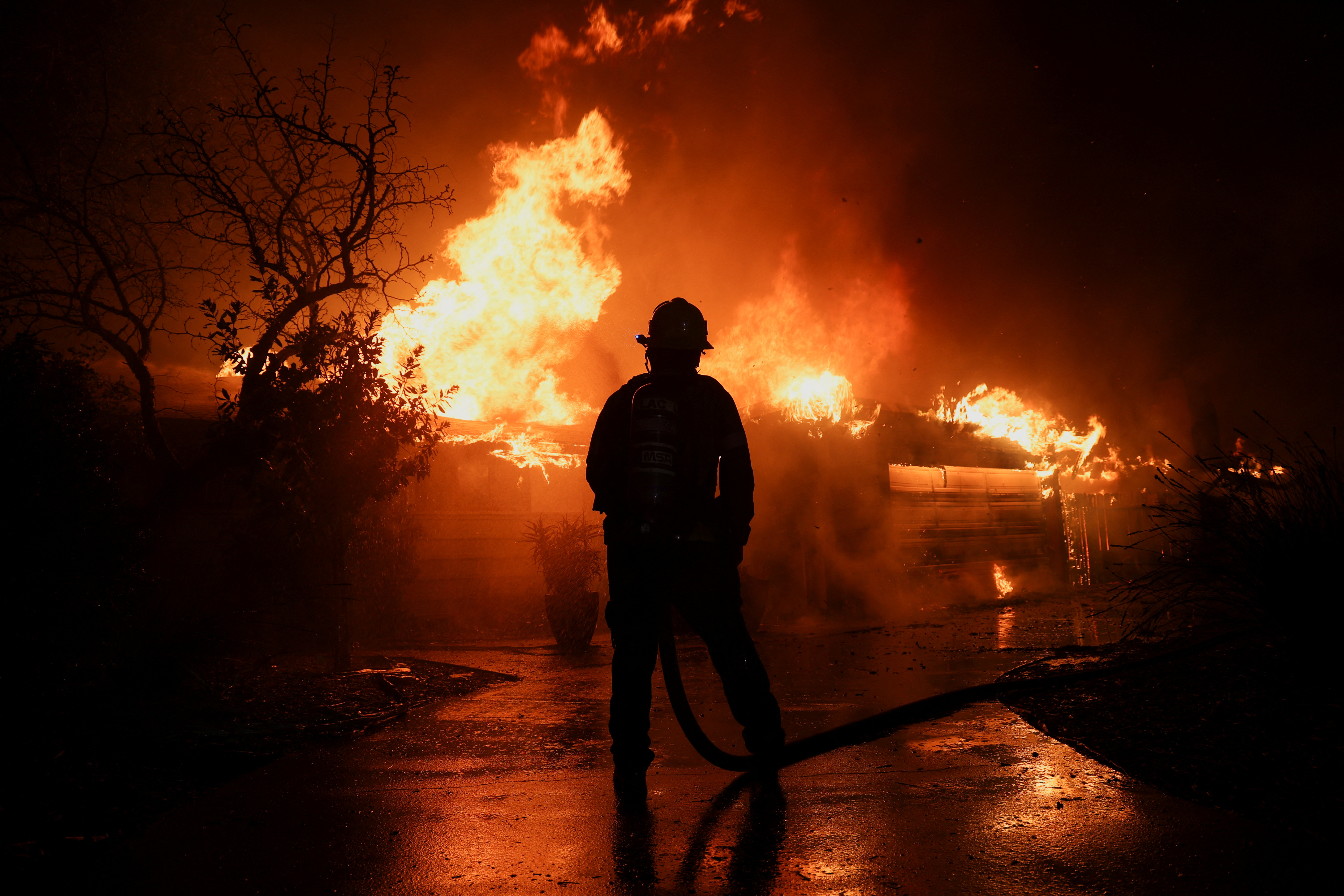 A firefighter works to extinguish flames as the Eaton Fire burns in Pasadena, California, U.S. January 8, 2025. REUTERS/Mario Anzuoni