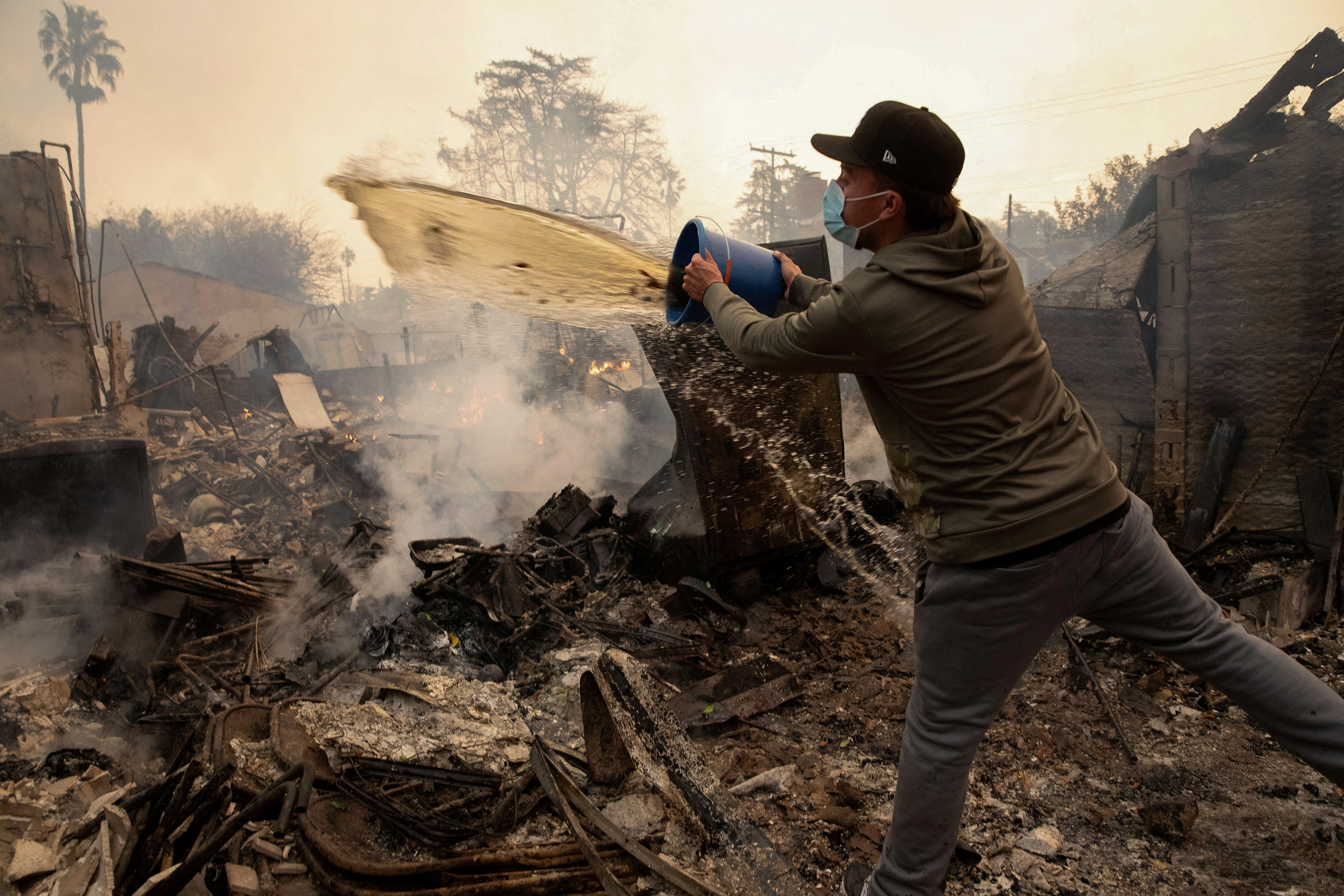A resident uses buckets of water following fires in Altadena, California, U.S. January 8, 2025. REUTERS/Zaydee Sanchez