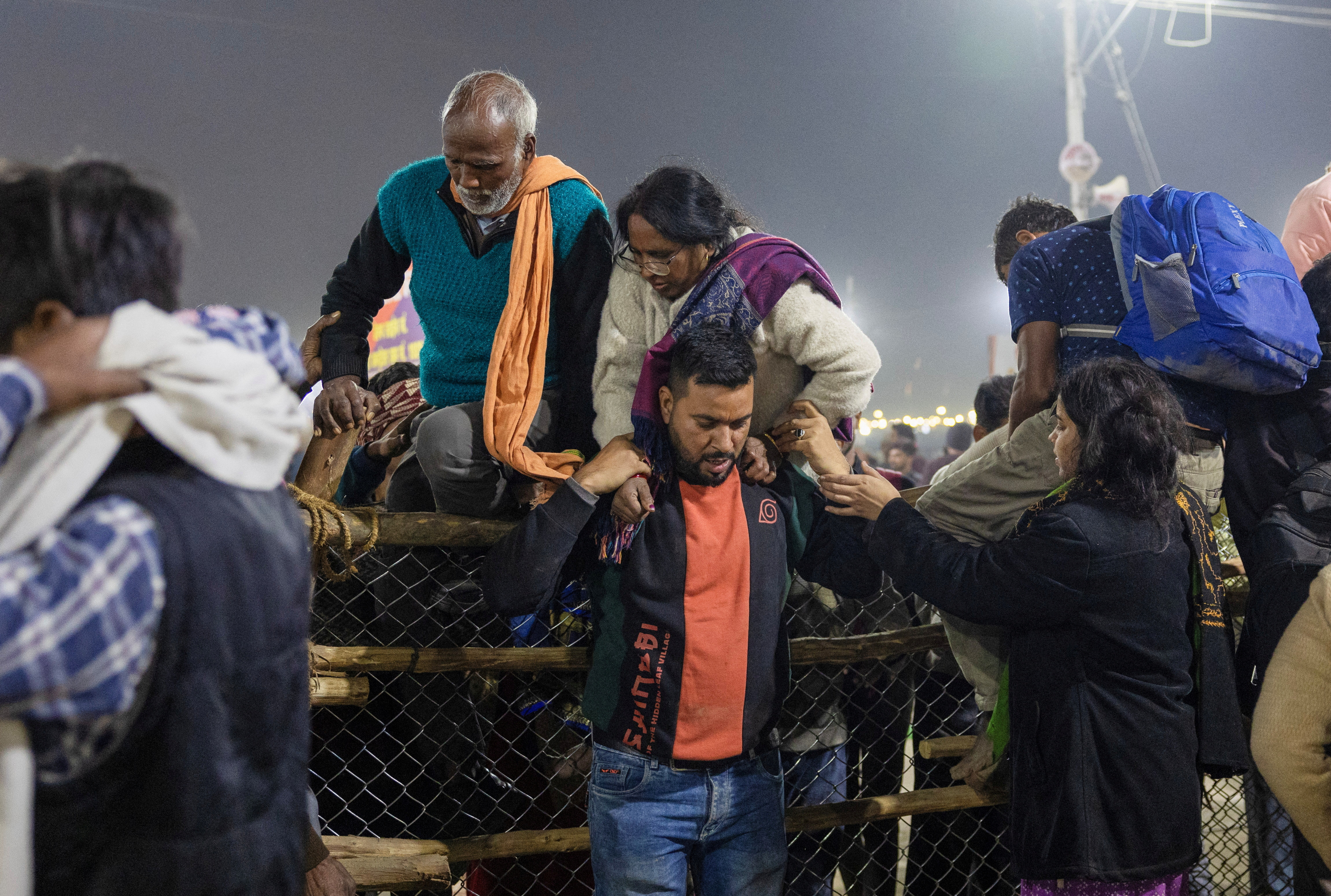 A man helps a relative cross over a barricade, after a deadly stampede before the second "Shahi Snan" (royal bath), at the "Maha Kumbh Mela" or the Great Pitcher Festival in Prayagraj, India January 29, 2025. REUTERS/Adnan Abidi