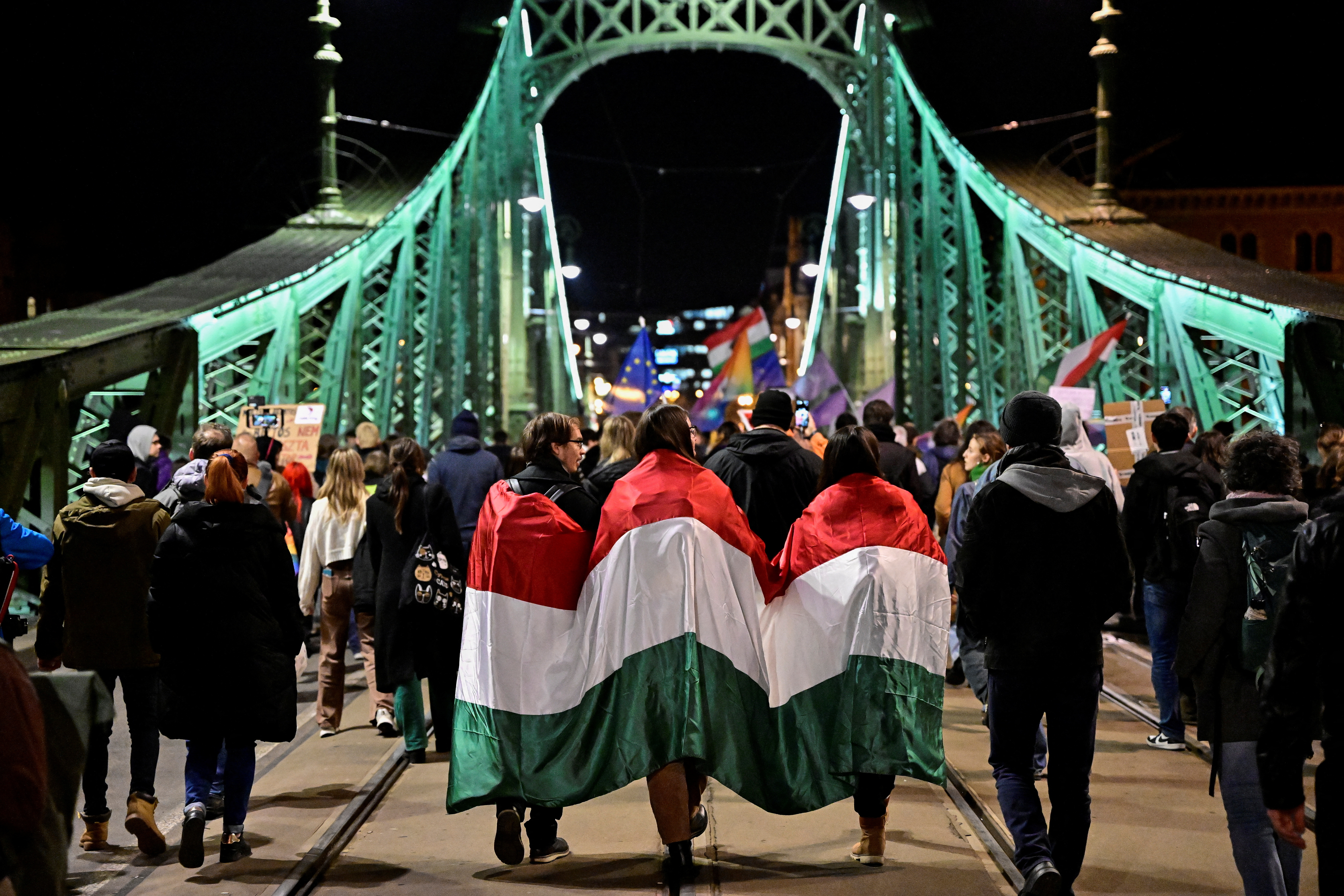 People covered in a Hungarian flag take part in a demonstration, after the Hungarian parliament passed a law that bans LGBTQ+ communities from holding the annual Pride march and allows a broader constraint on freedom of assembly, in Budapest, Hungary, March 25, 2025. REUTERS/Marton Monus