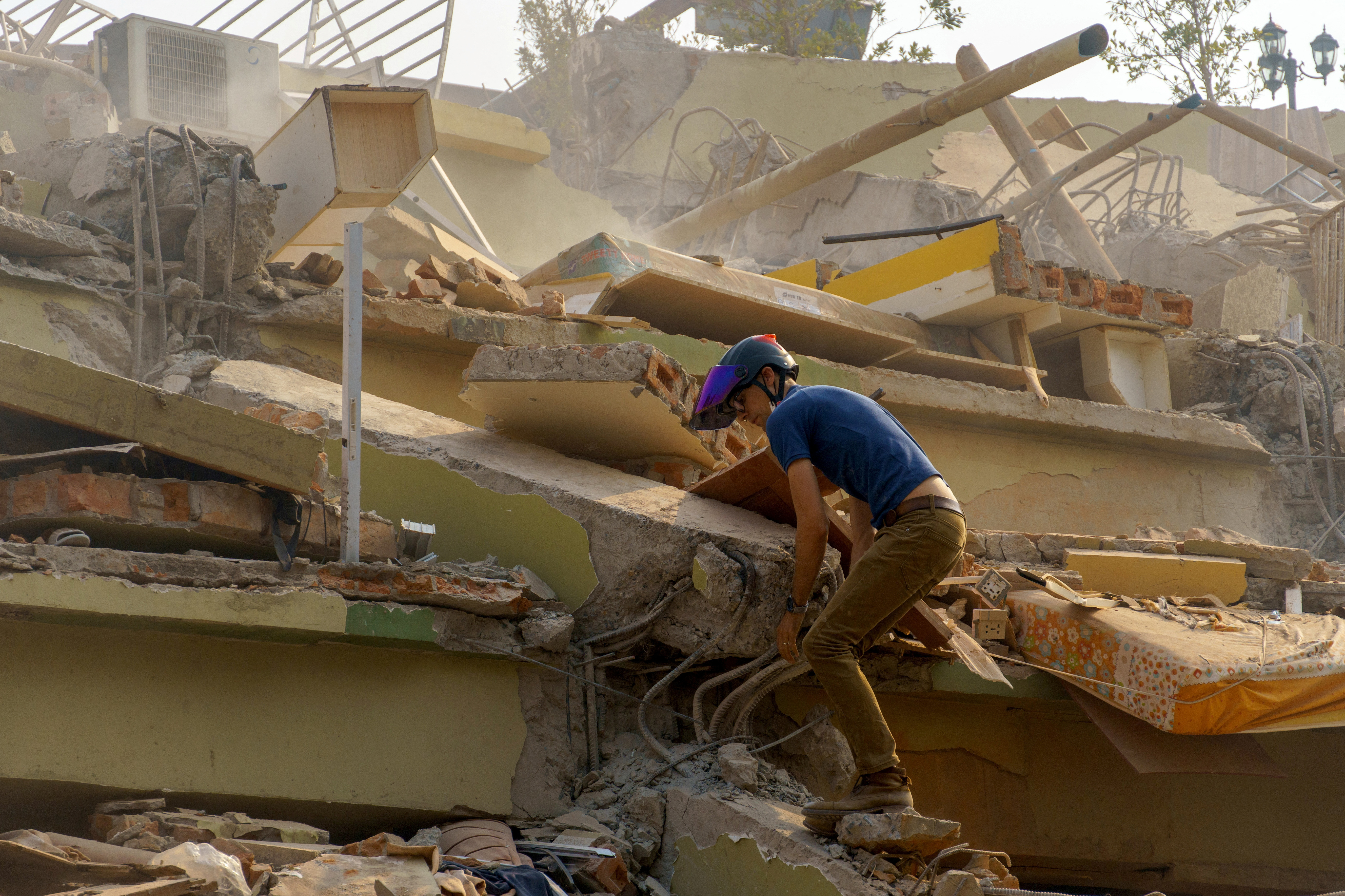A man walks the rubble of the building that collapsed following a strong earthquake, in Mandalay, Myanmar, March 29, 2025. REUTERS/Stringer