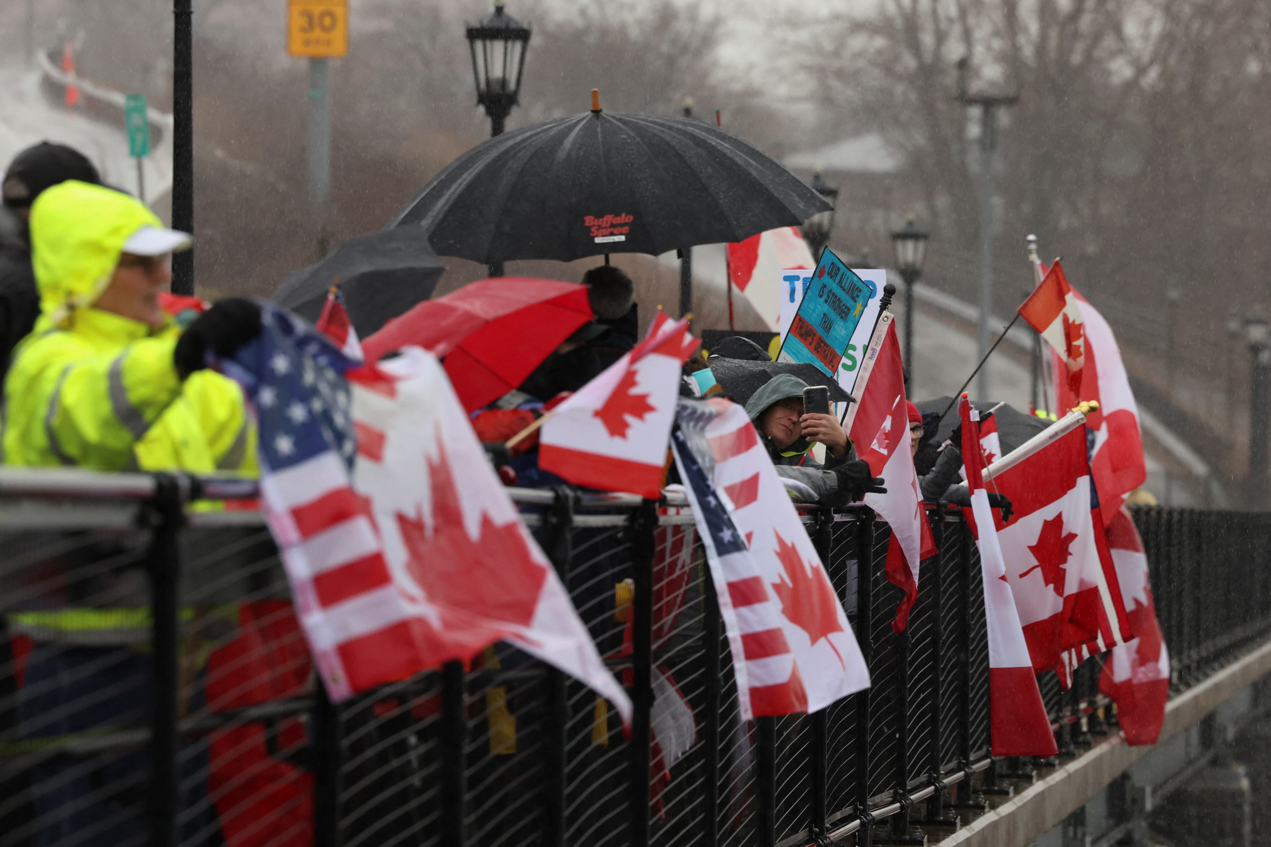 People hold flags as they protest in solidarity with Canada amid uncertainty over tariffs policy, near the Canada-U.S. border crossing in Buffalo, New York, U.S. April 2, 2025. REUTERS/Lindsay DeDario