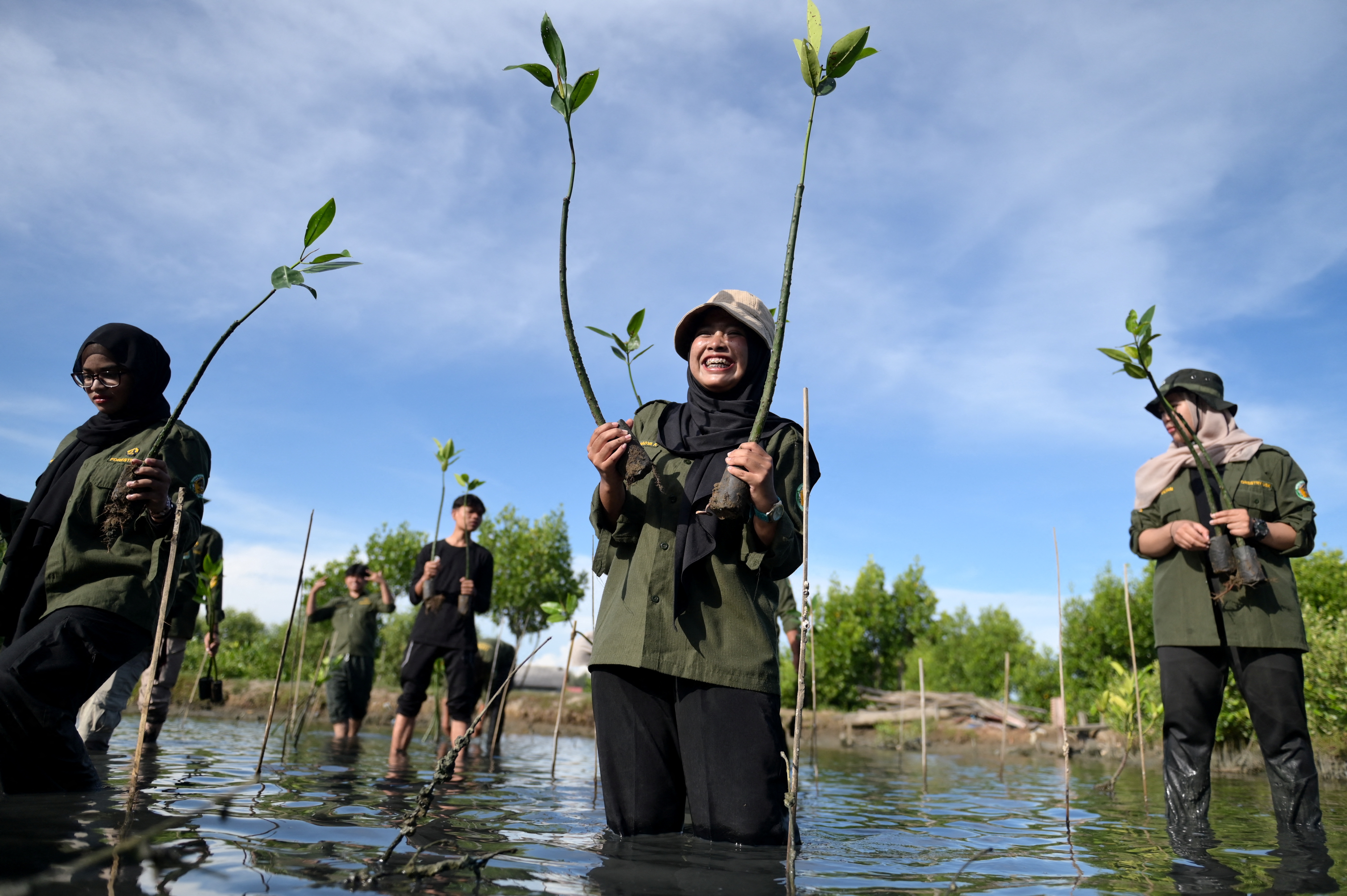 University student react as they take part in mangrove planting to mark Earth Day in Banda Aceh, Indonesia, April 22, 2025. REUTERS/Riska Munawarah
