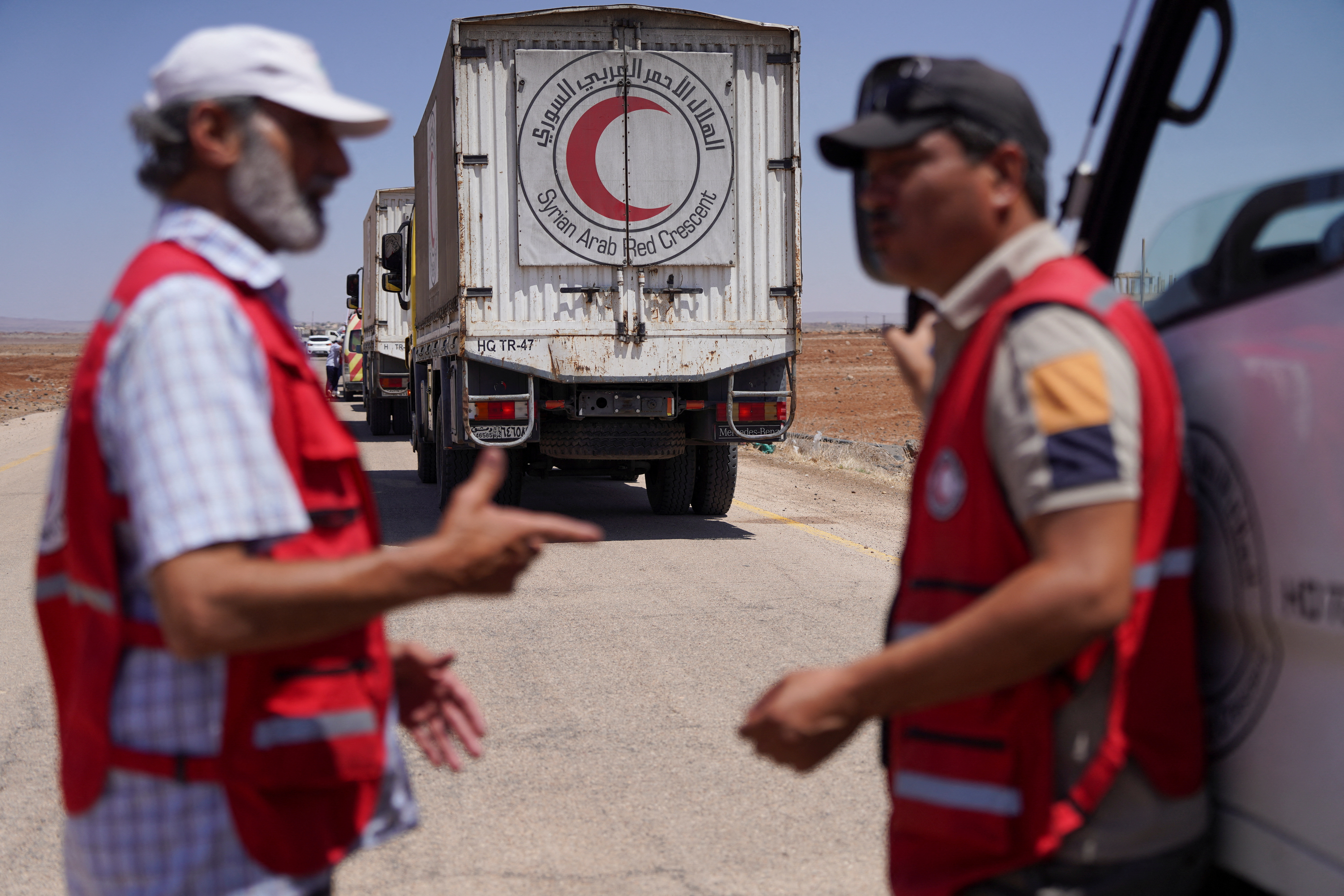 Workers of Syrian Arab Red Crescent stand next to a vehicle carrying aid as they make their way to Sweida, at Bosra al-Sham town, near Deraa, Syria July 23, 2025. REUTERS/Karam al-Masri
