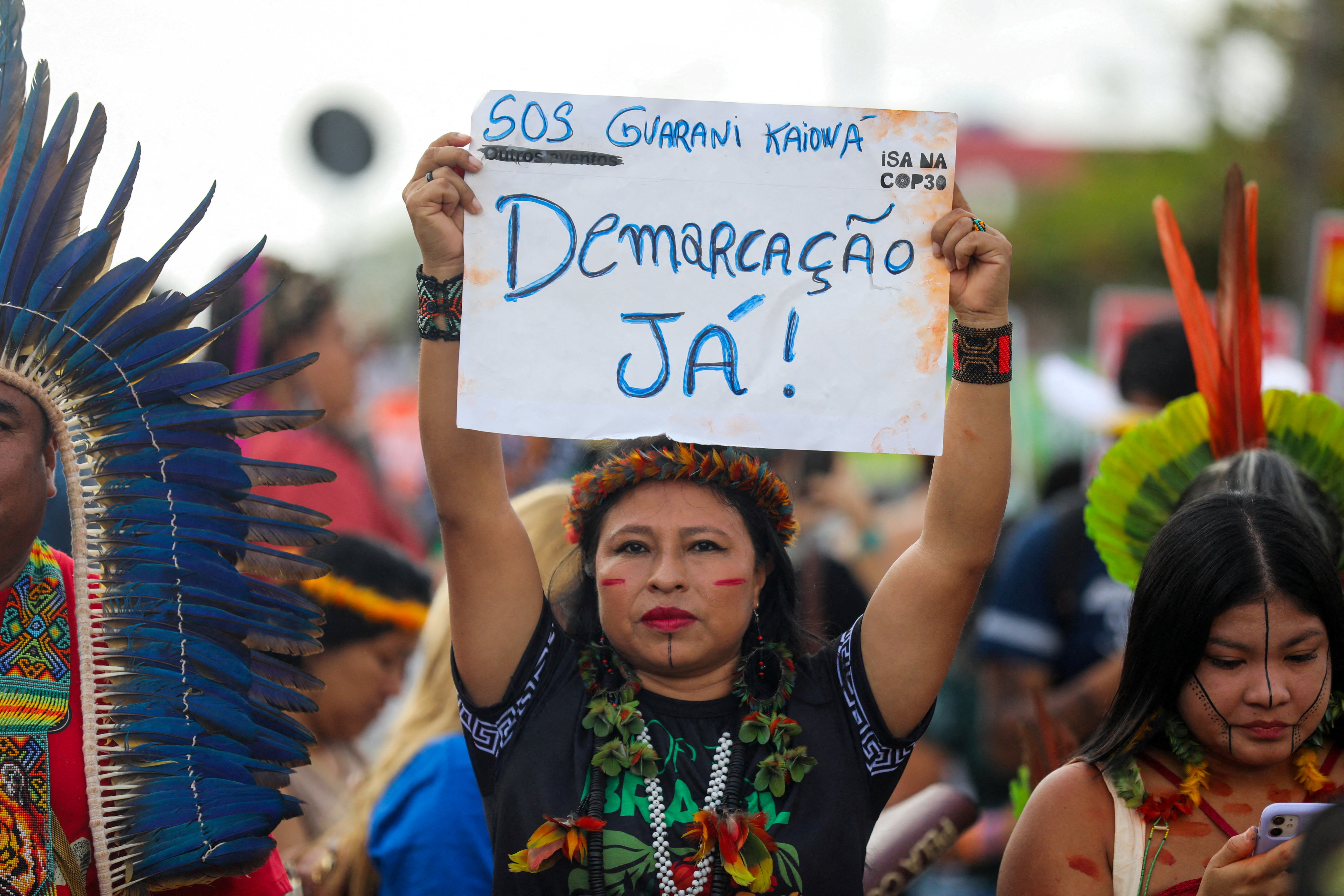 An indigenous woman holds a sign reading: "Demarcation now!", during a protest to call for climate justice and territorial protection during the U.N. Climate Change Conference (COP30), in Belem, Brazil, November 17, 2025. REUTERS/Anderson Coelho