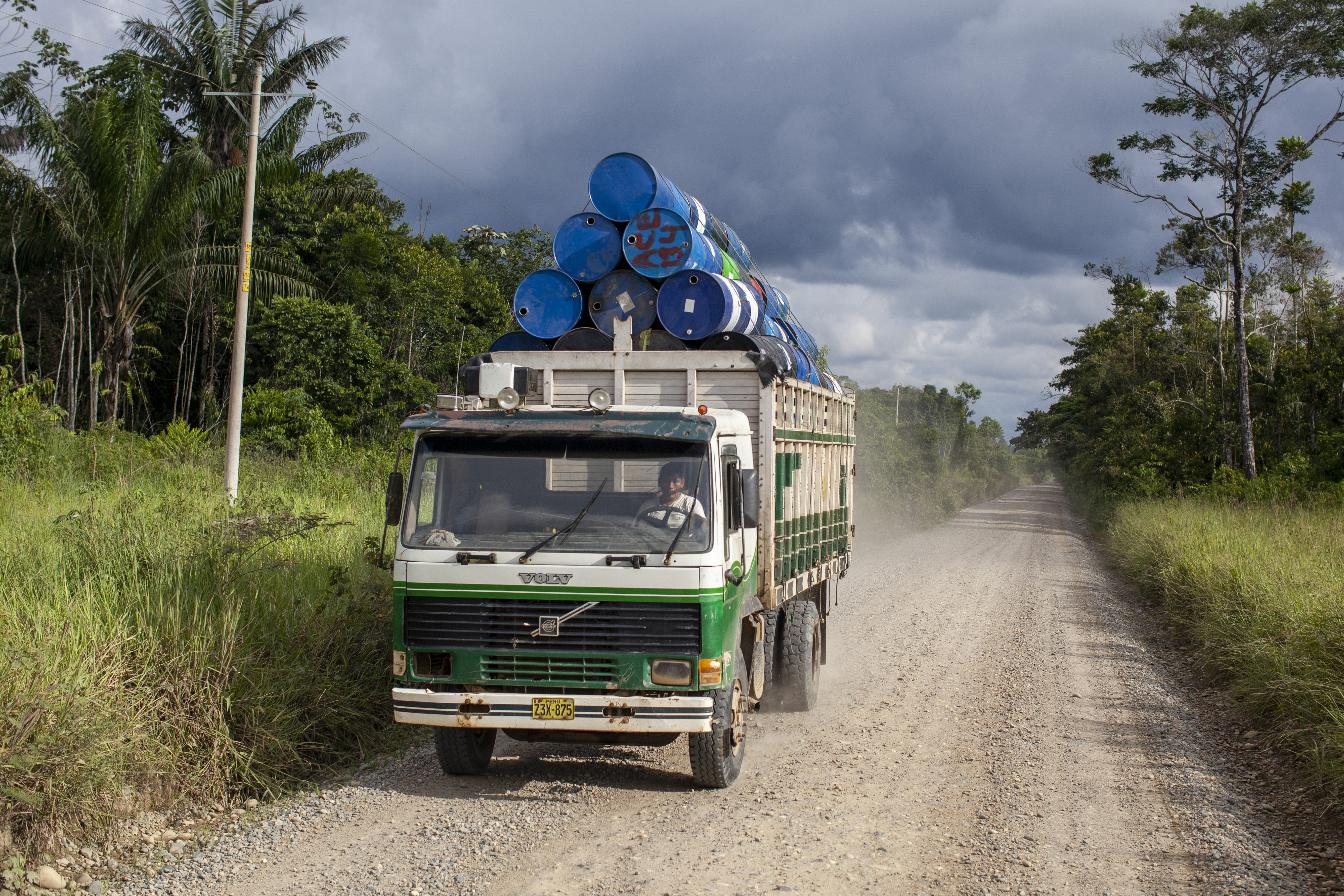 A truck transports barrels used in gold mining along the road to Delta 1, a mining settlement in the Amazon rainforest of Madre de Dios, Peru. The barrels are commonly repurposed as flotation devices. Madre de Dios, Peru. March 9, 2022. Alejandro Saldívar/Environmental Investigation Agency/Handout via Thomson Reuters Foundation