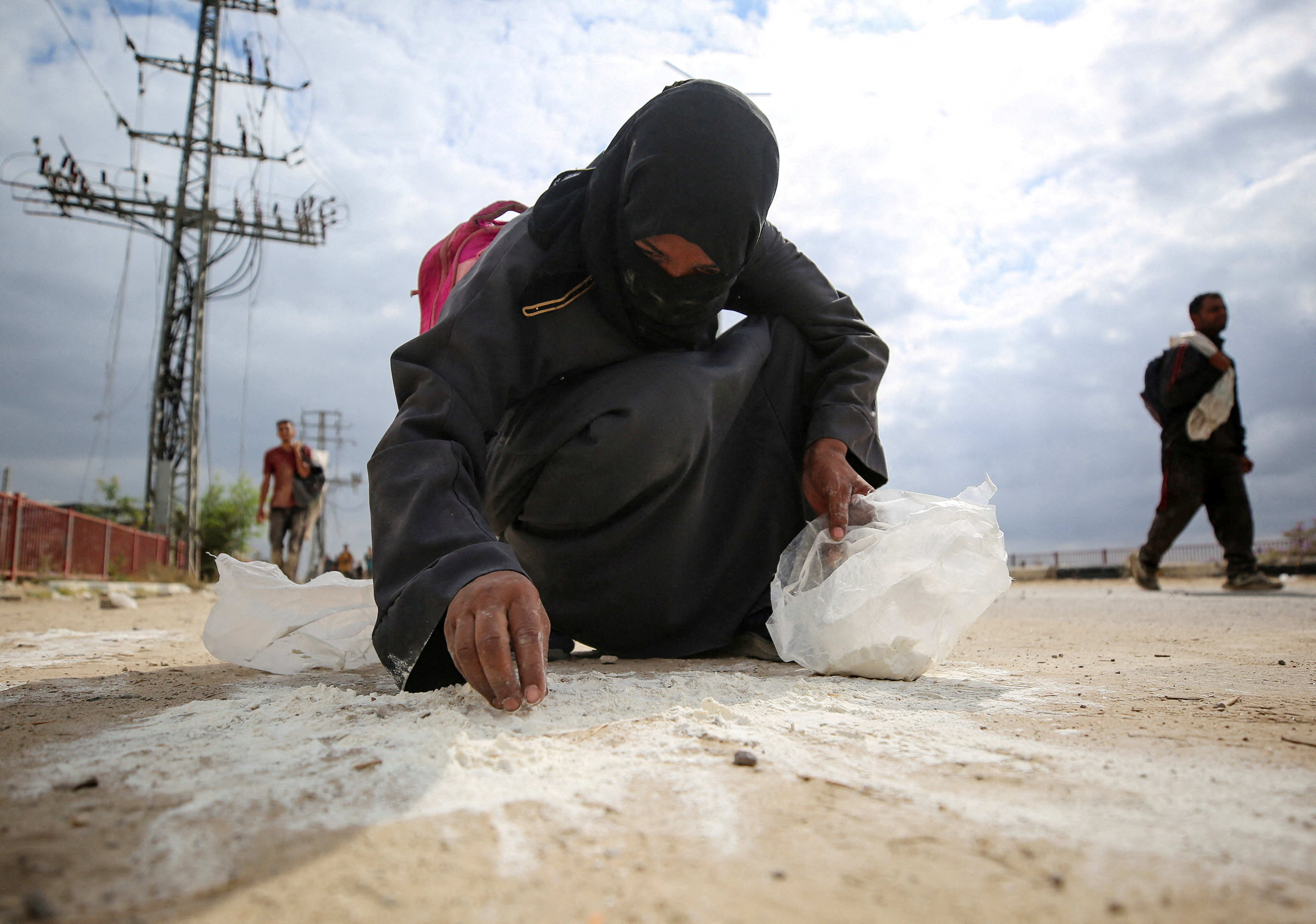 A woman collects flour from the ground as Palestinians receive aid supplies from the Gaza Humanitarian Foundation (GHF) in Gaza, August 1, 2025. REUTERS/Stringer