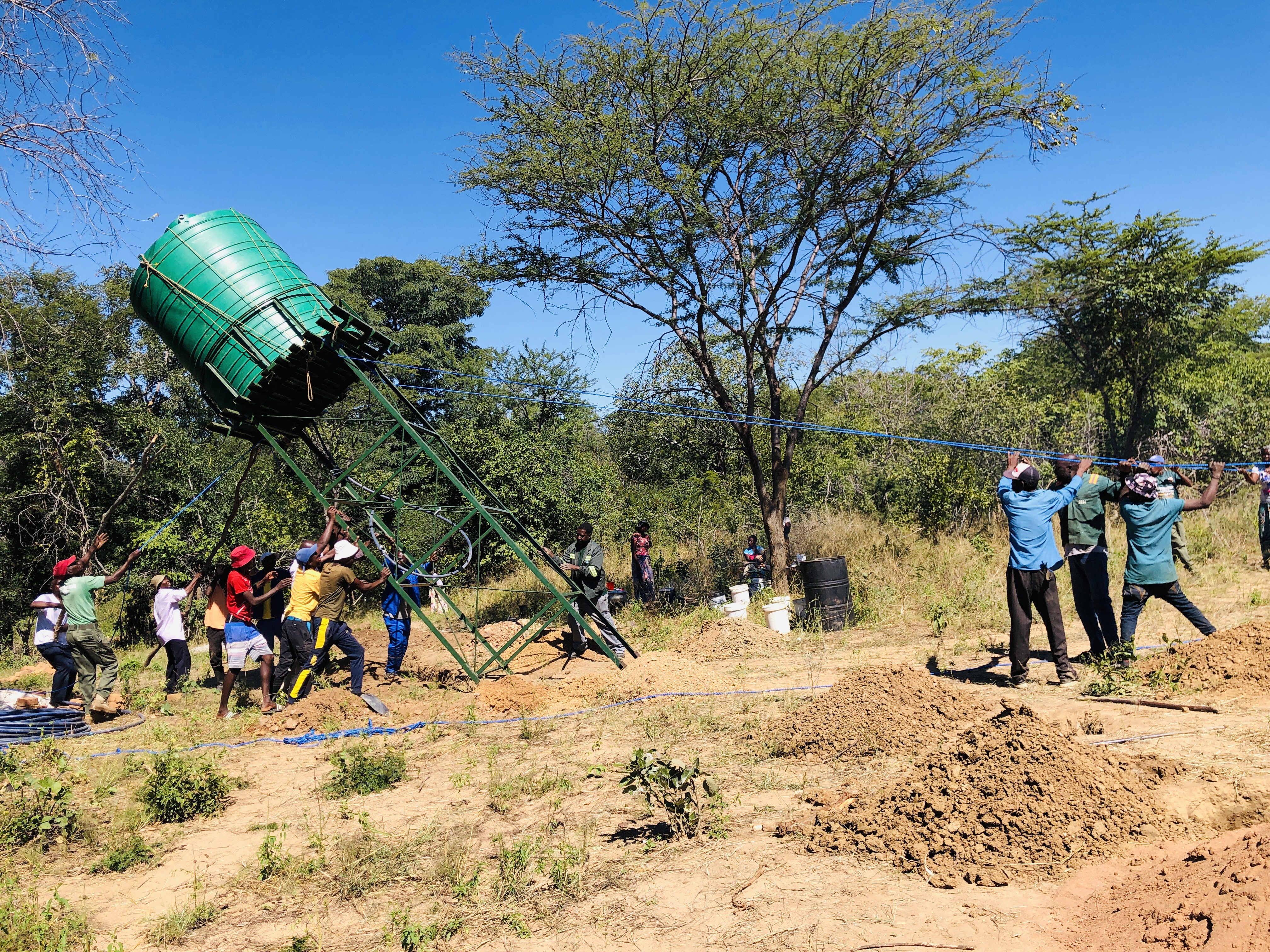Suanyanga villagers put up a water tank for a borehole that will be powered by a solar system. The Ilaja Permaculture Garden and solar system was donated to the community through a collaboration between Soft Foot Alliance, Painted Dog Conservation, and Mother Africa. 7 May 2025. Lungelo Ndhlovu/Thomson Reuters Foundation.