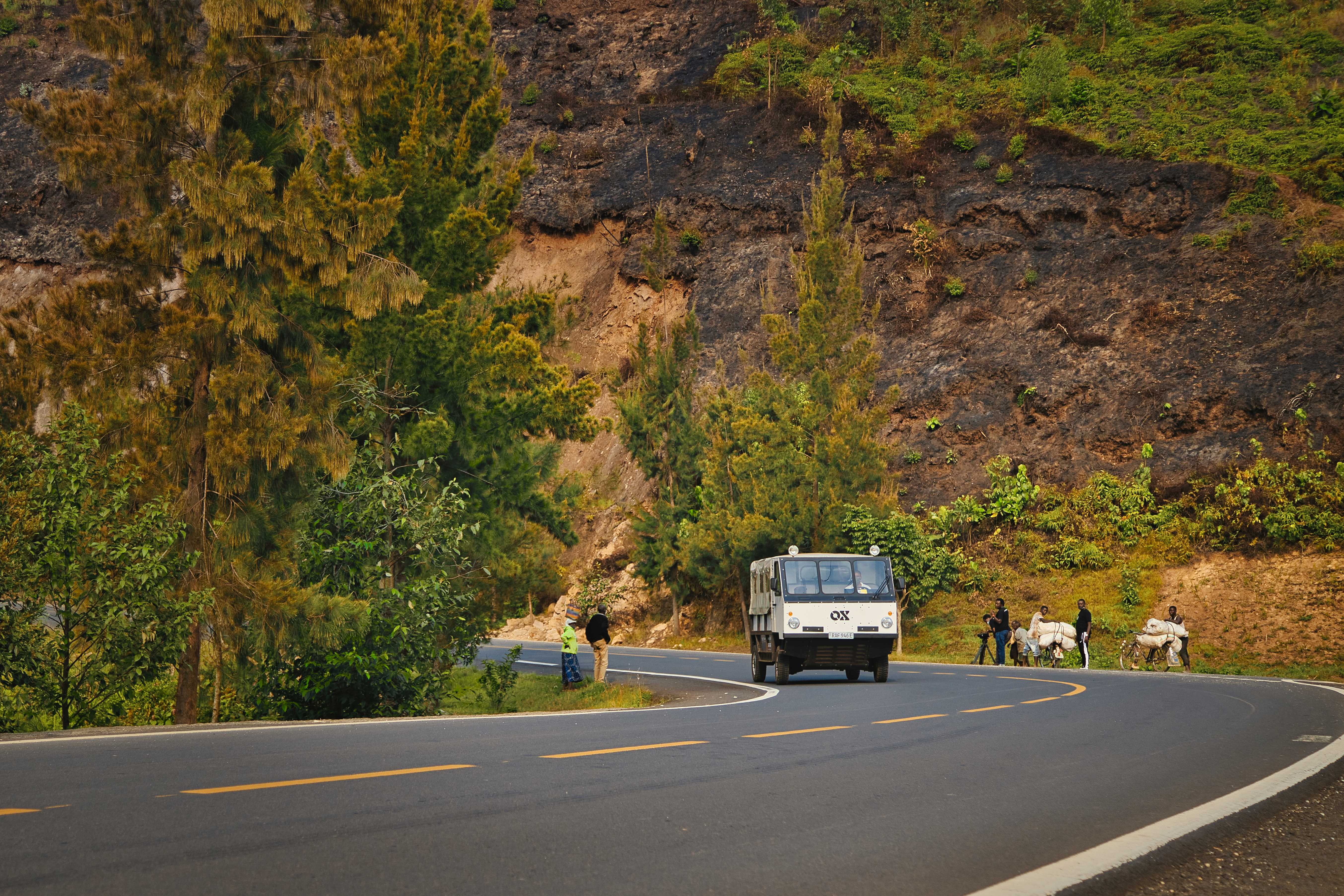 An electric OX truck drives past cyclists carrying heavy loads in Nyamasheke, Rwanda. September 14, 2021. Thomson Reuters Foundation/ Handout via OX.