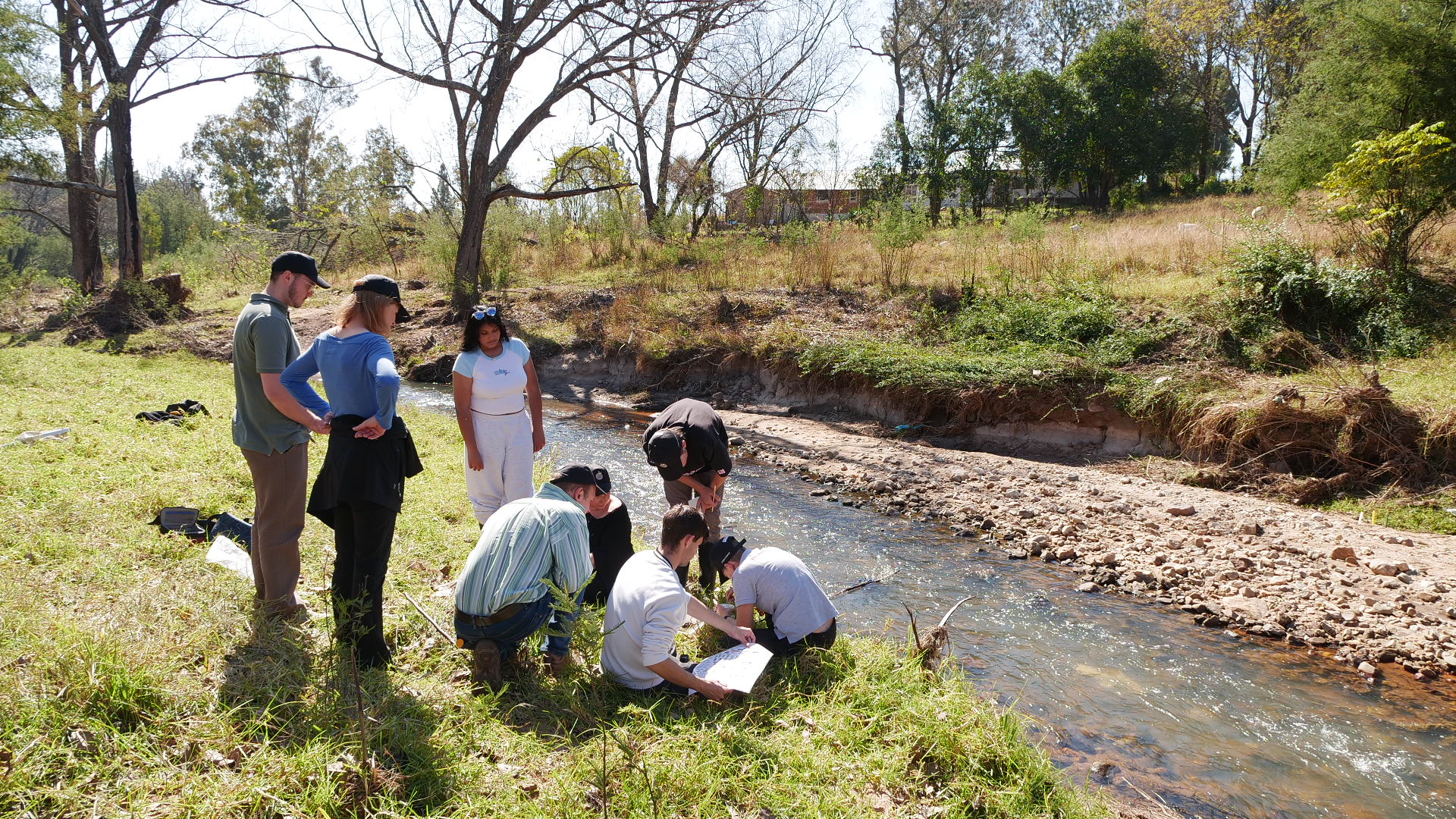 IIE MSA students and staff gather around a water sample at the Wilgespruit river to test the water quality in Johannesburg, South Africa, May 29, 2025. Thomson Reuters Foundation/Kim Harrisberg