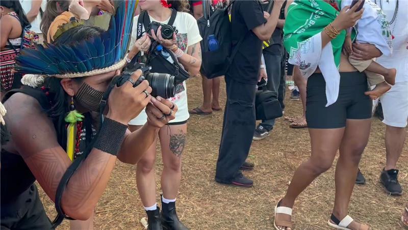 An Indigenous takes photos from protestors at the Free Land Camp in Brasilia, Brazil, April 10, 2025. Thomson Reuters Foundation/André Cabette Fábio